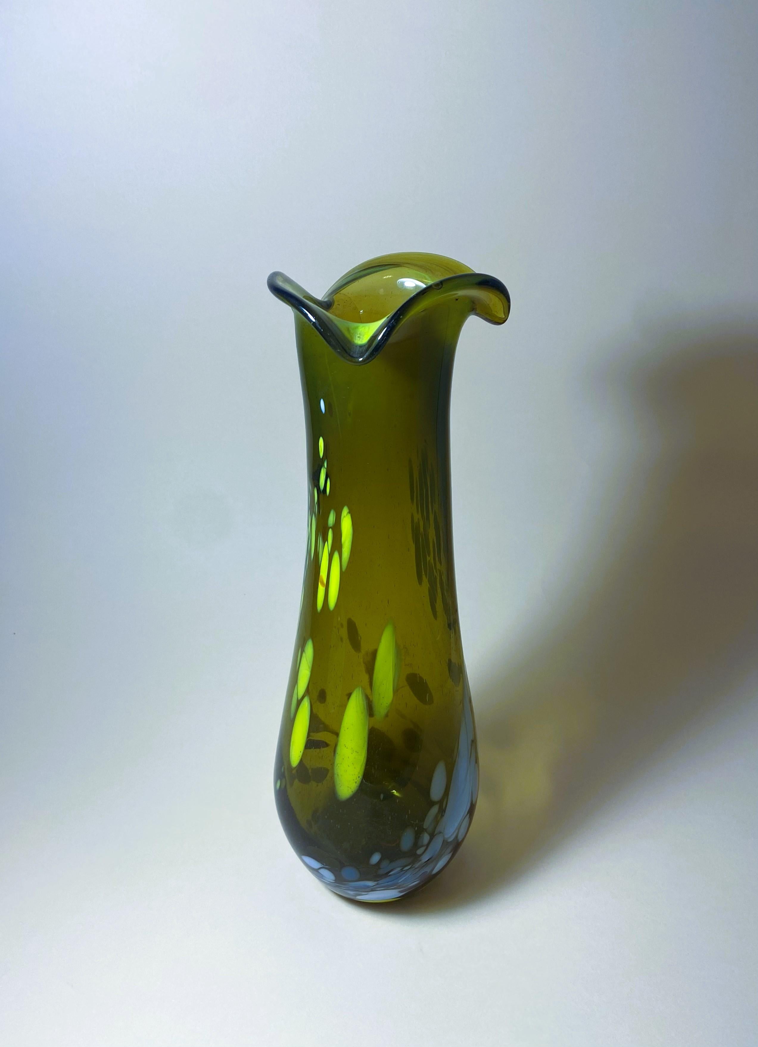 Questo vaso in vetro vintage è un pezzo unico che aggiungerà un tocco di moderna eleganza a qualsiasi spazio. Realizzato a mano in Ungheria da Budveszel Gyula negli anni '90, questo vaso presenta un design colorato ed è realizzato in vetro soffiato