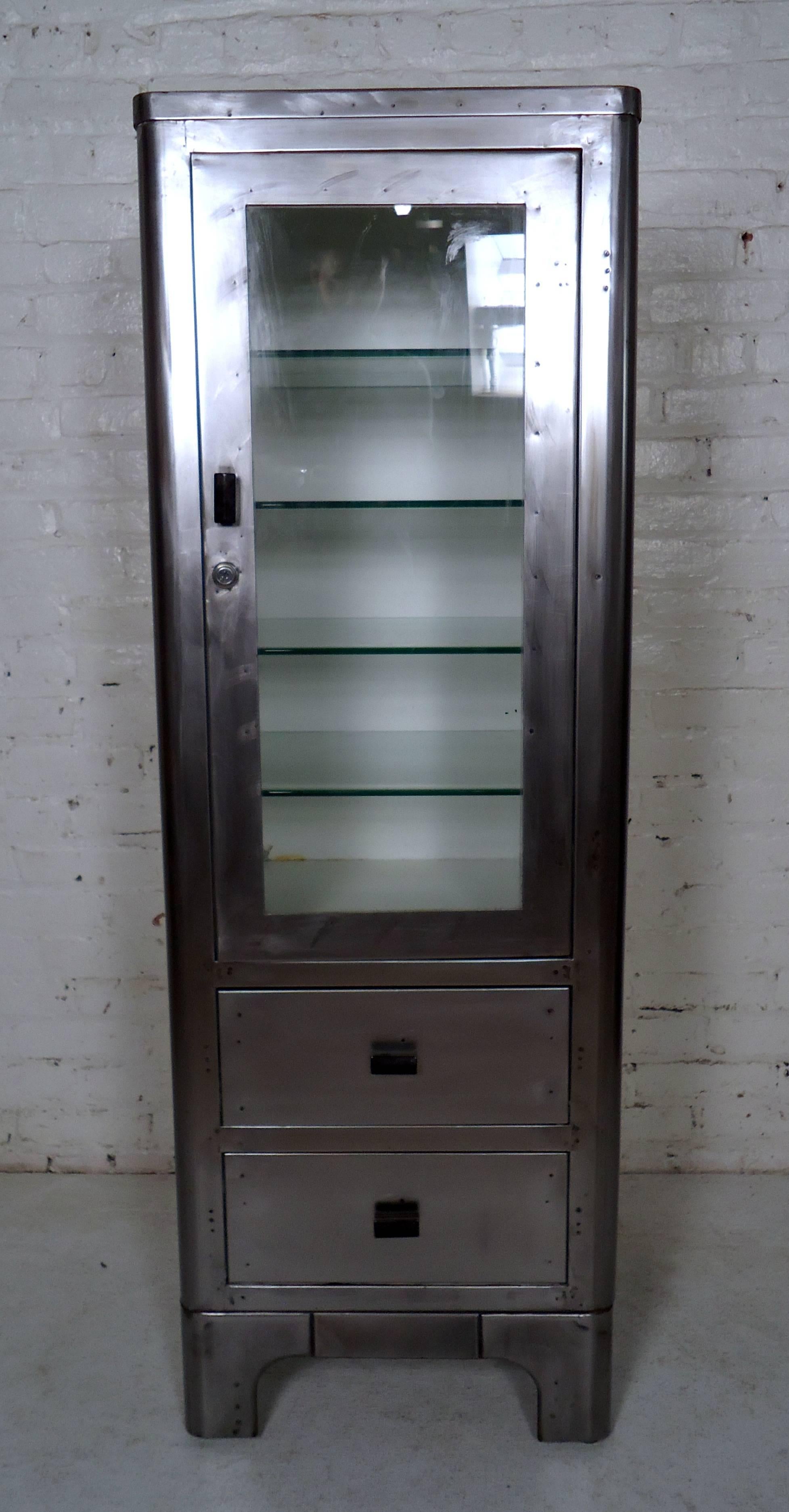 Vintage medical cabinet stripped to bare metal and lacquered for a handsome industrial look. Two lower drawers, top cabinet featuring many glass shelves. 

Please confirm item location - NY or NJ - with dealer).