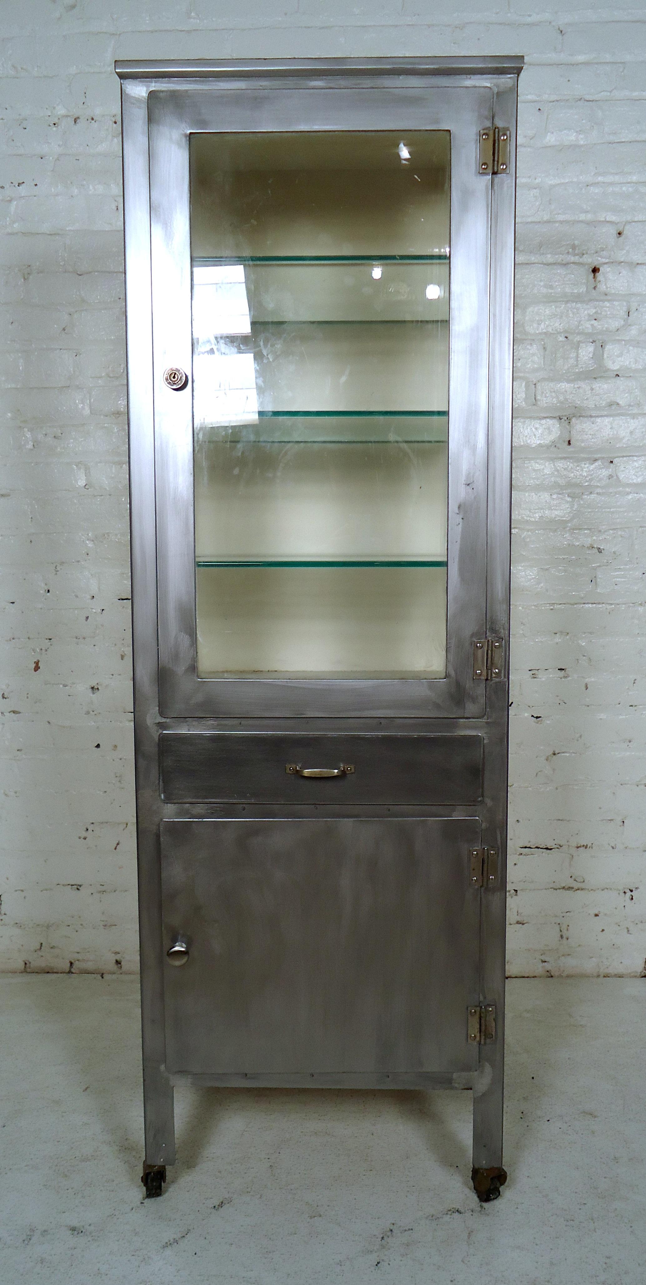 Vintage medical cabinet stripped to bare metal and lacquered for a handsome industrial look. Two lower drawers, top cabinet featuring many glass shelves on wheels.

Please confirm item location - NY or NJ - with dealer).

