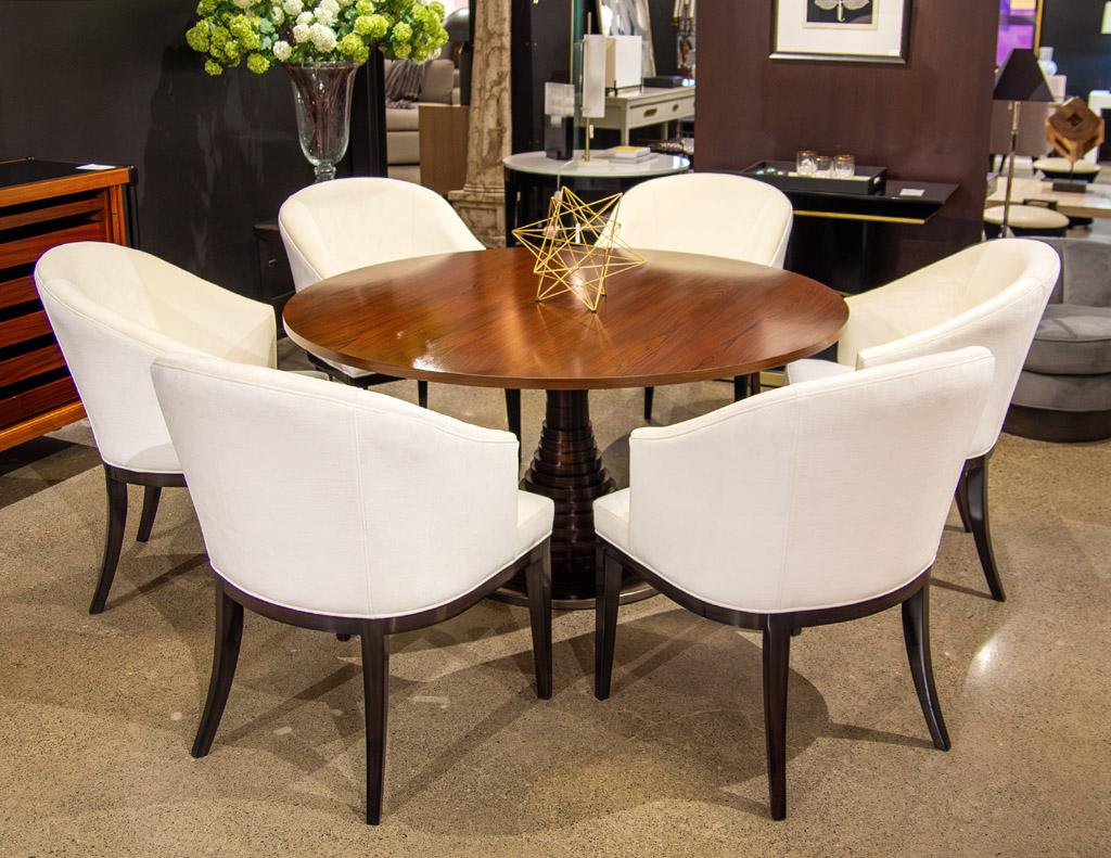 This exquisite round vintage modern Italian dining table, designed by the renowned Carlo Di Carli, is crafted from luxurious rosewood material and features a unique geometric pedestal design with metal accent ring. This one of a kind table dates