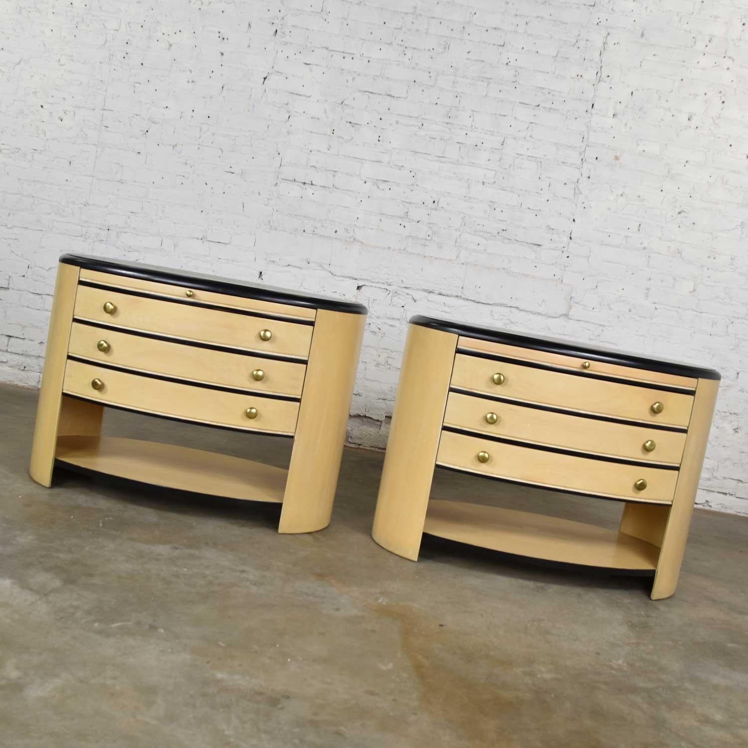 Handsome pair of modern oval nightstands or bedside cabinets in a blonde whitewash and black finish. They are in wonderful condition. We have restored the black top. There may still be signs of age appropriate wear but nothing outstanding. There is