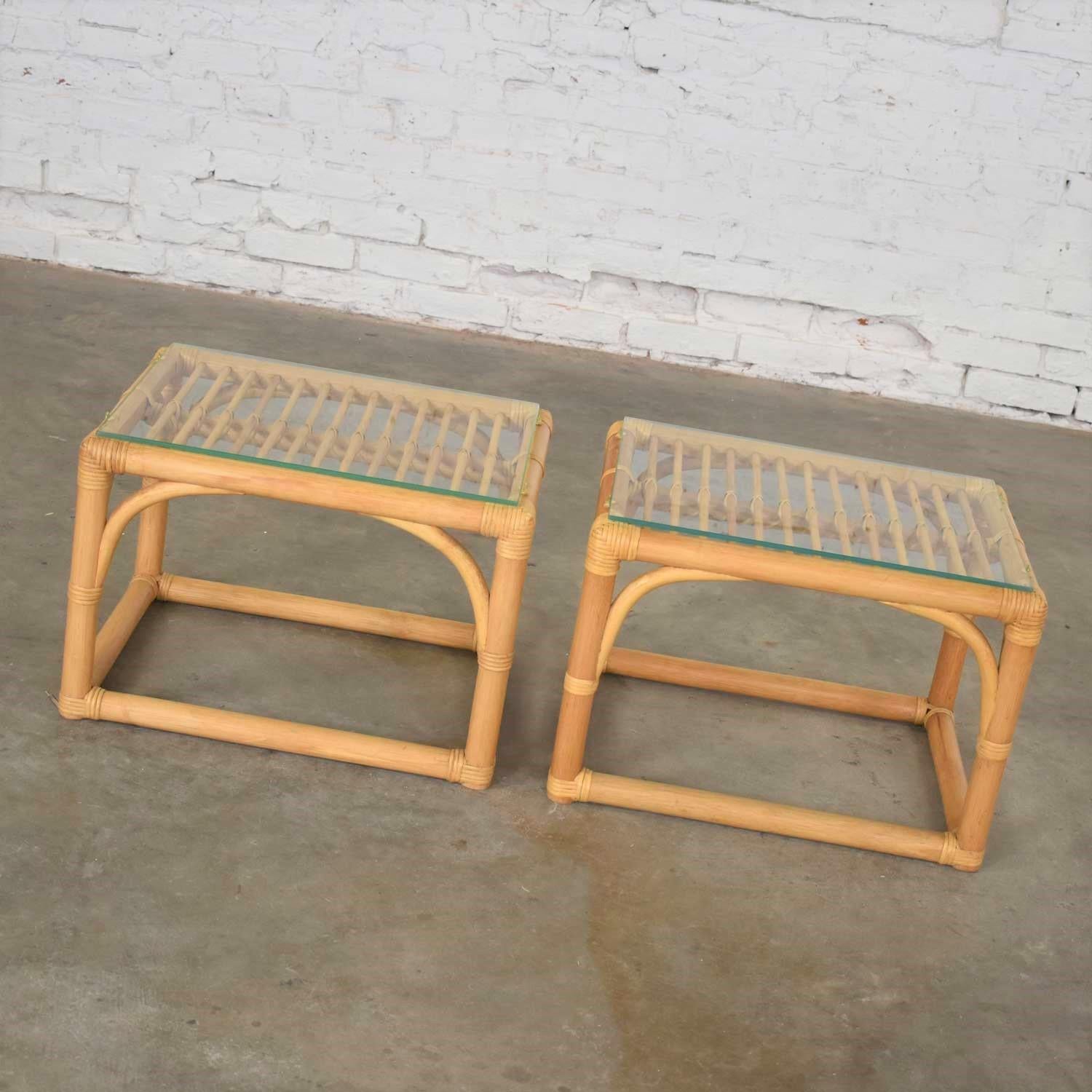 Handsome modern pair of rattan rectangular side tables or end tables with a glass top. They are in fabulous vintage condition with no outstanding flaws we have detected. Glass may have minor scratching. Please see photos, circa