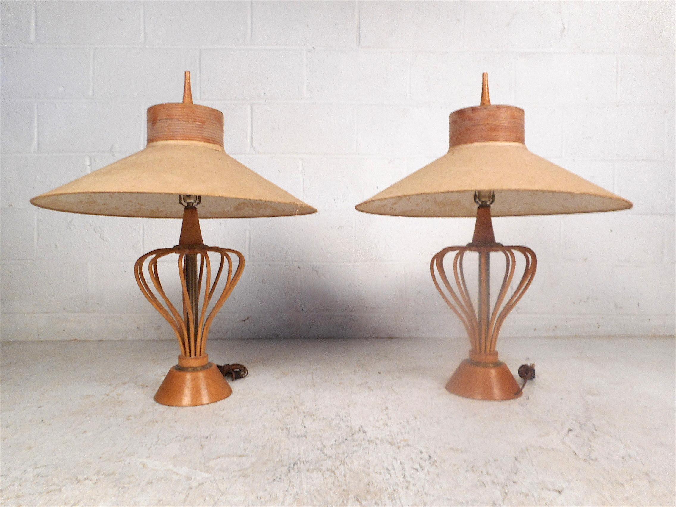 Unusual pair of midcentury lamps. Stylish and unique design with an array of sculpted wooden rods which give these lamps an interesting look. The brass columns which span the center of the lamps along with oversized shades add to the allure. These
