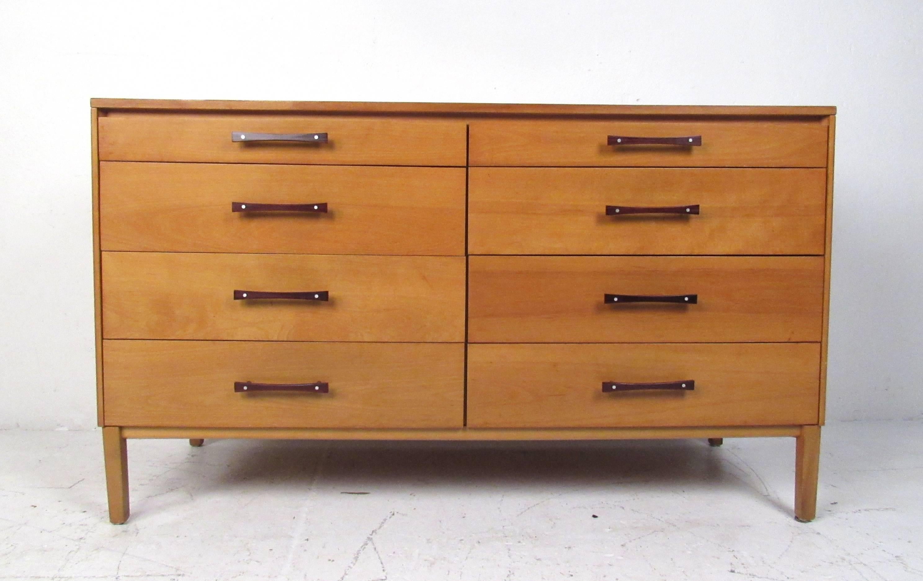 This beautiful Mid-Century Modern dresser features eight drawers with sculpted bow-tie shaped pulls made of Brazilian rosewood. A straight line design with a stunning blonde maple case and graduated drawers. This Paul McCobb, Perimeter group case