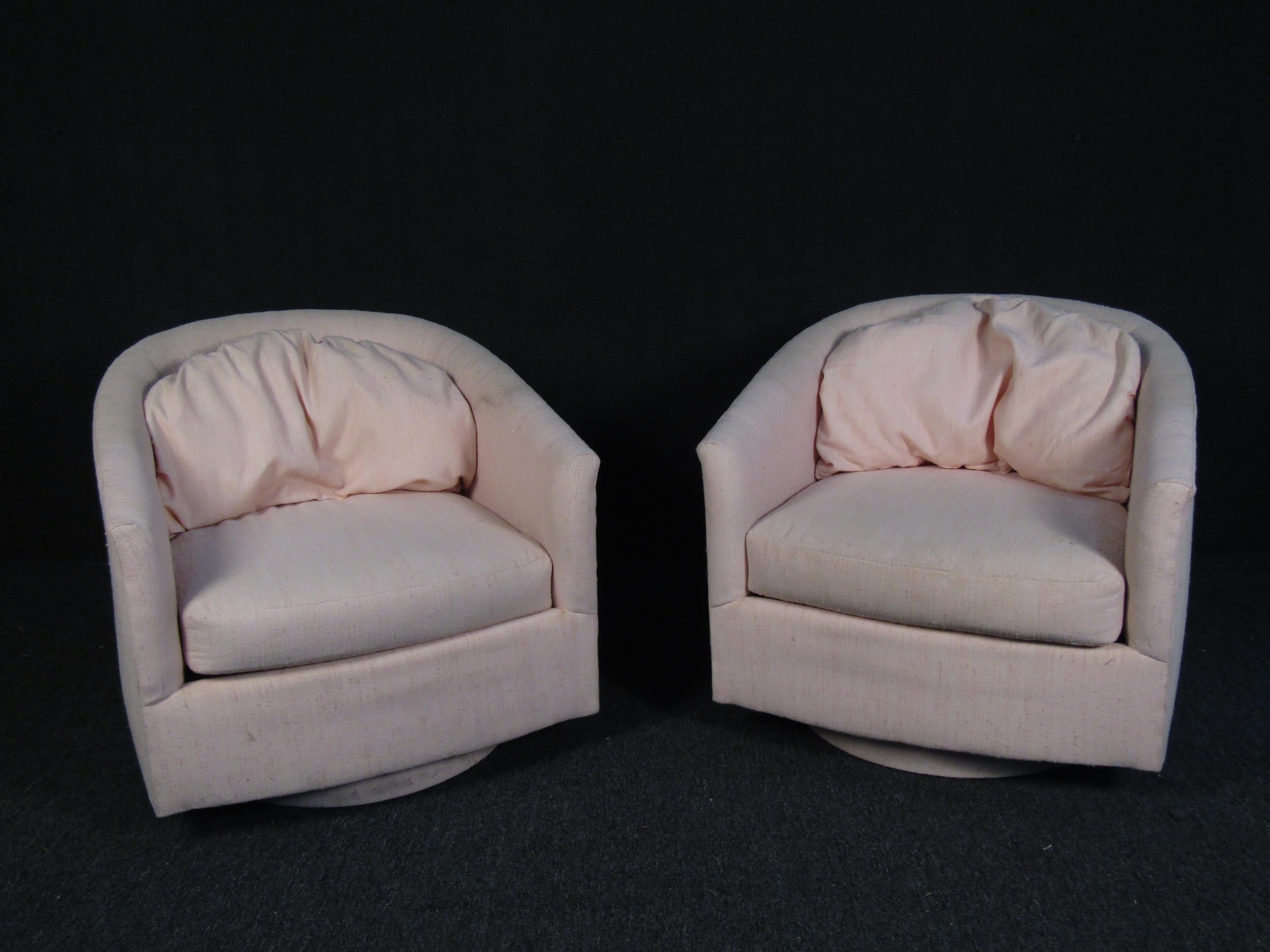 Une paire élégante de chaises vintage modernes à dossier en forme de tonneau, avec un dossier duveteux et un siège épais rembourré. Une base pivotante couverte offre la commodité sans sacrifier le style. Cette paire de chaises longues est le