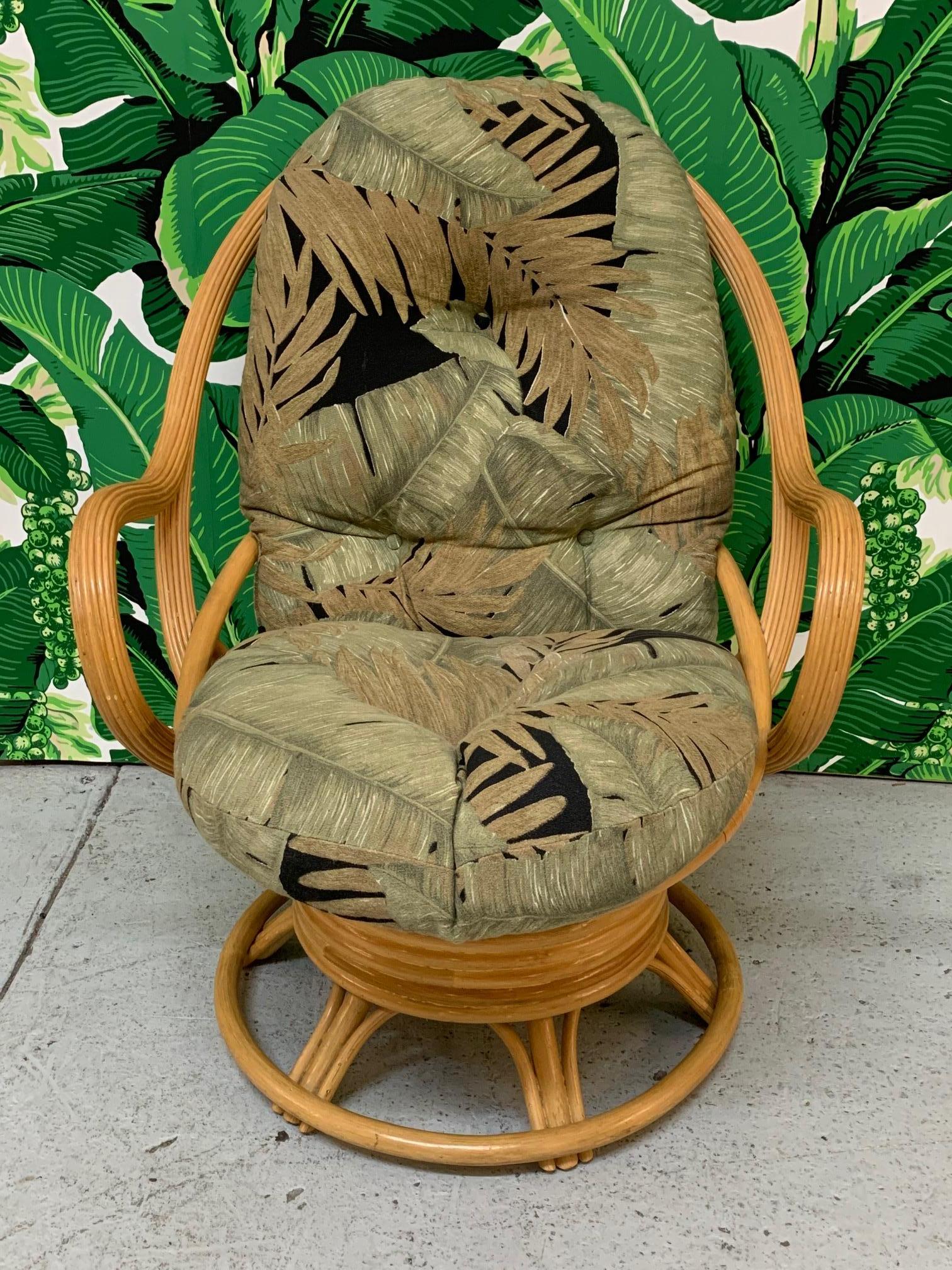 Rattan lounge chair features both swivel and rocking movement, and thick, comfortable upholstery in a tropical print, circa 1970s. Good vintage condition with minor imperfections consistent with age.