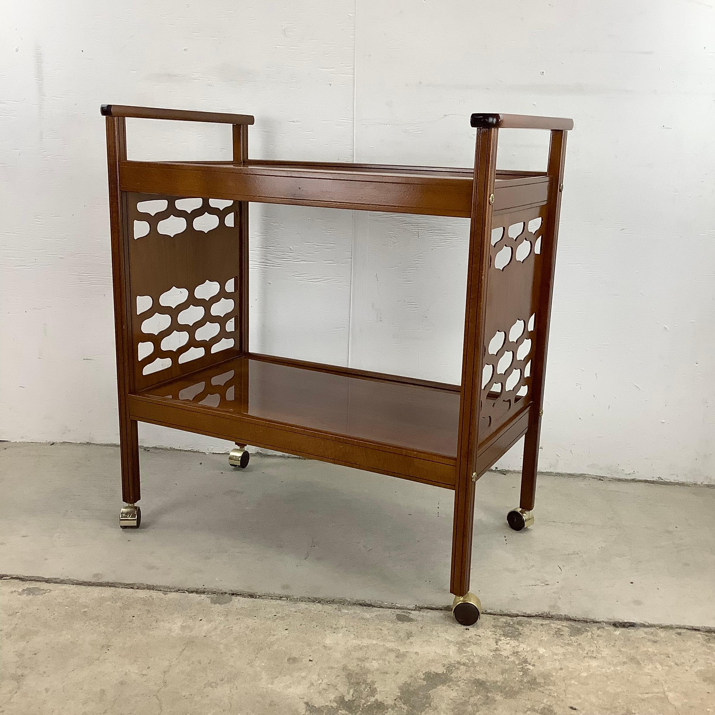 This two tier rolling bar cart or tea cart features MCM style decorative sides with wide open shelves for plenty of storage. Easily rolls from room to room for barware storage, display, or drink service. 

Dimensions: 30w 18d 33h 11.5 lower level