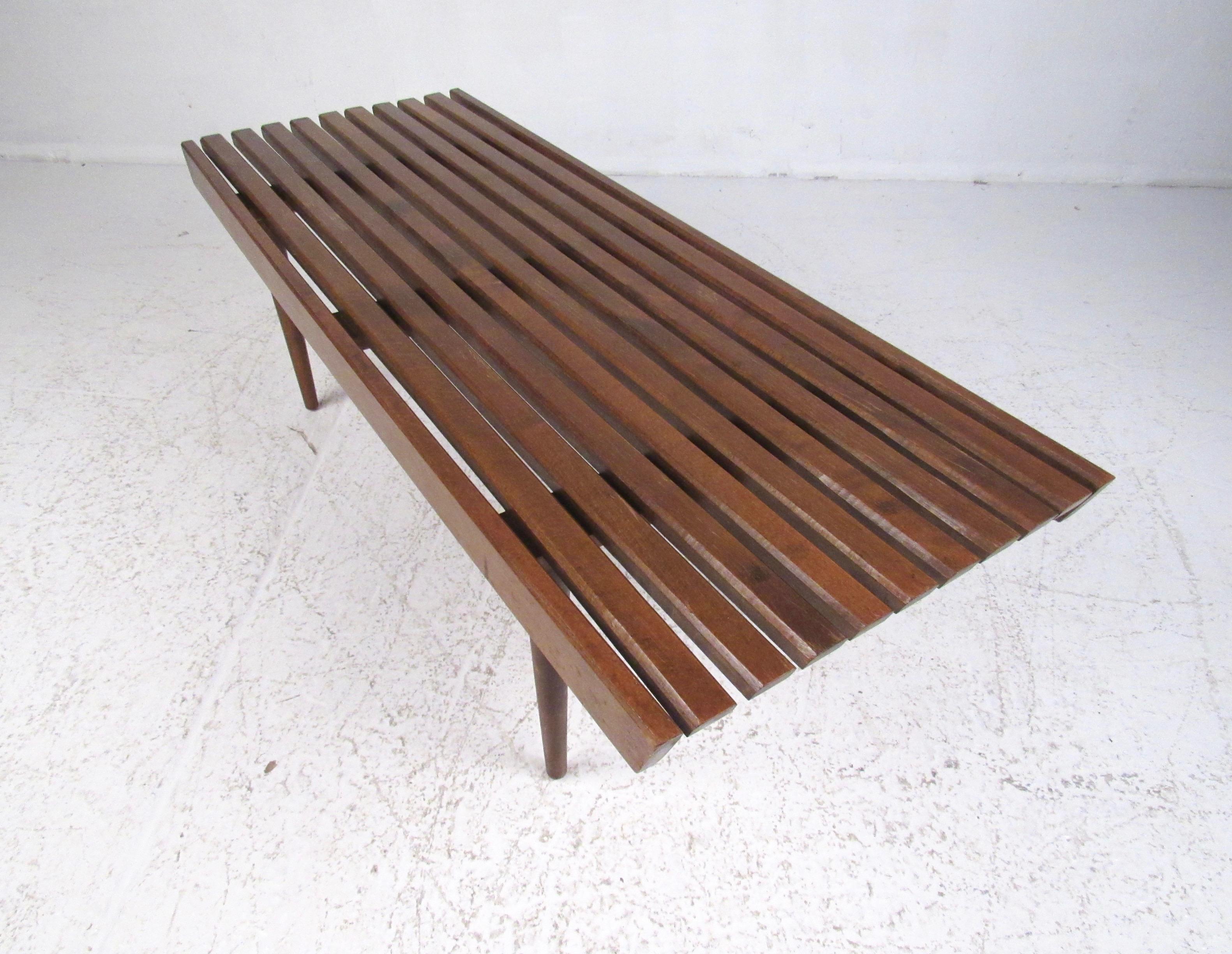 This Mid-Century Modern coffee table features vintage walnut slat construction and tapered removable legs. Simple yet stylish design makes this the perfect piece for use as a bench for occasional seating, or a living room cocktail table. Please