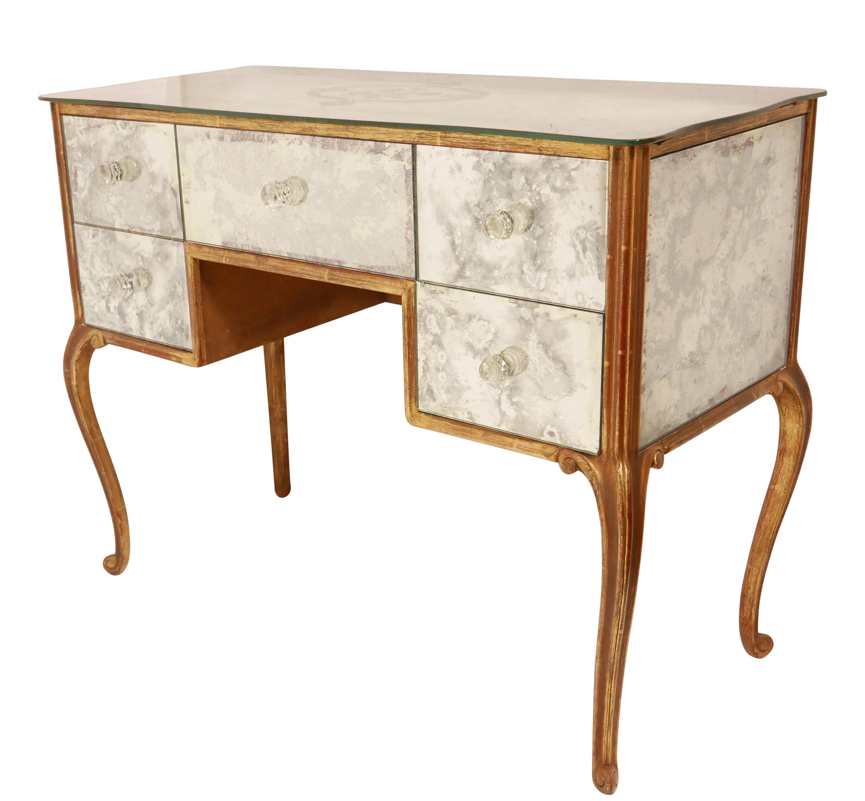 A modern Venetian style gilt dressing table or vanity with Smokey glass panels, the top with etched cartouche highlighted with gilt decoration. A center drawer flanked by pair of drawers all with glass knobs standing on cabriole legs.
Vintage