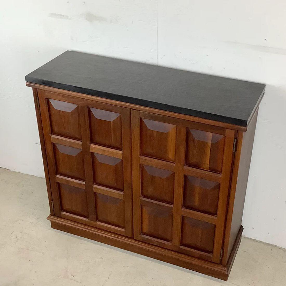 This uniquely narrow cabinet features sculpted door fronts and shelved interior in a beautiful vintage walnut finish- textured stone top adds a brutalist quality to this mid-century cabinet while the narrow footprint makes it a versatile storage