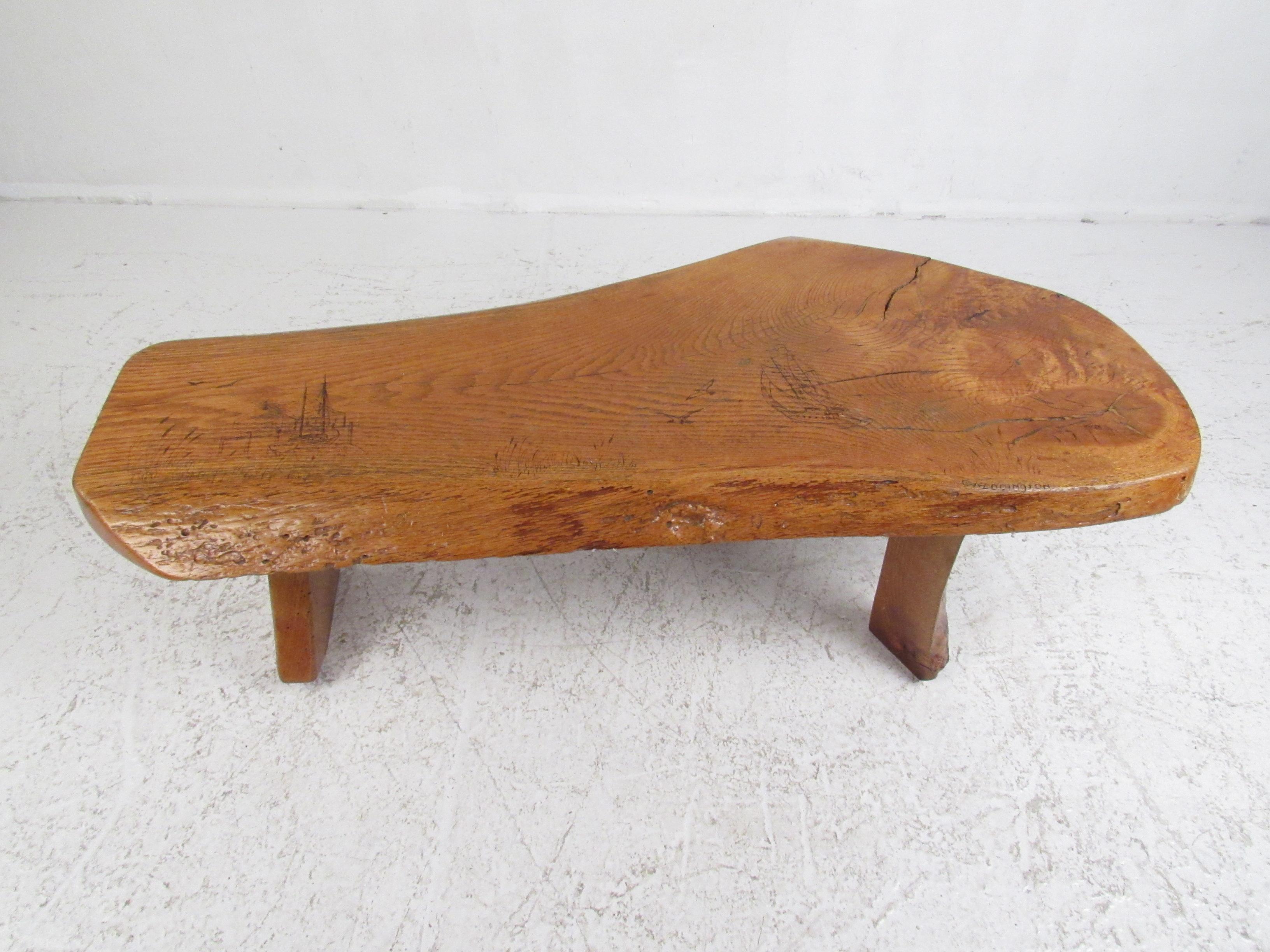 This stunning Mid-Century Modern coffee table features a freeform top and sculpted live edge legs. This unique handmade piece is signed G. Reddington. A small carved sailboat with seagulls and a marina with cattail weeds is carved on the top. The