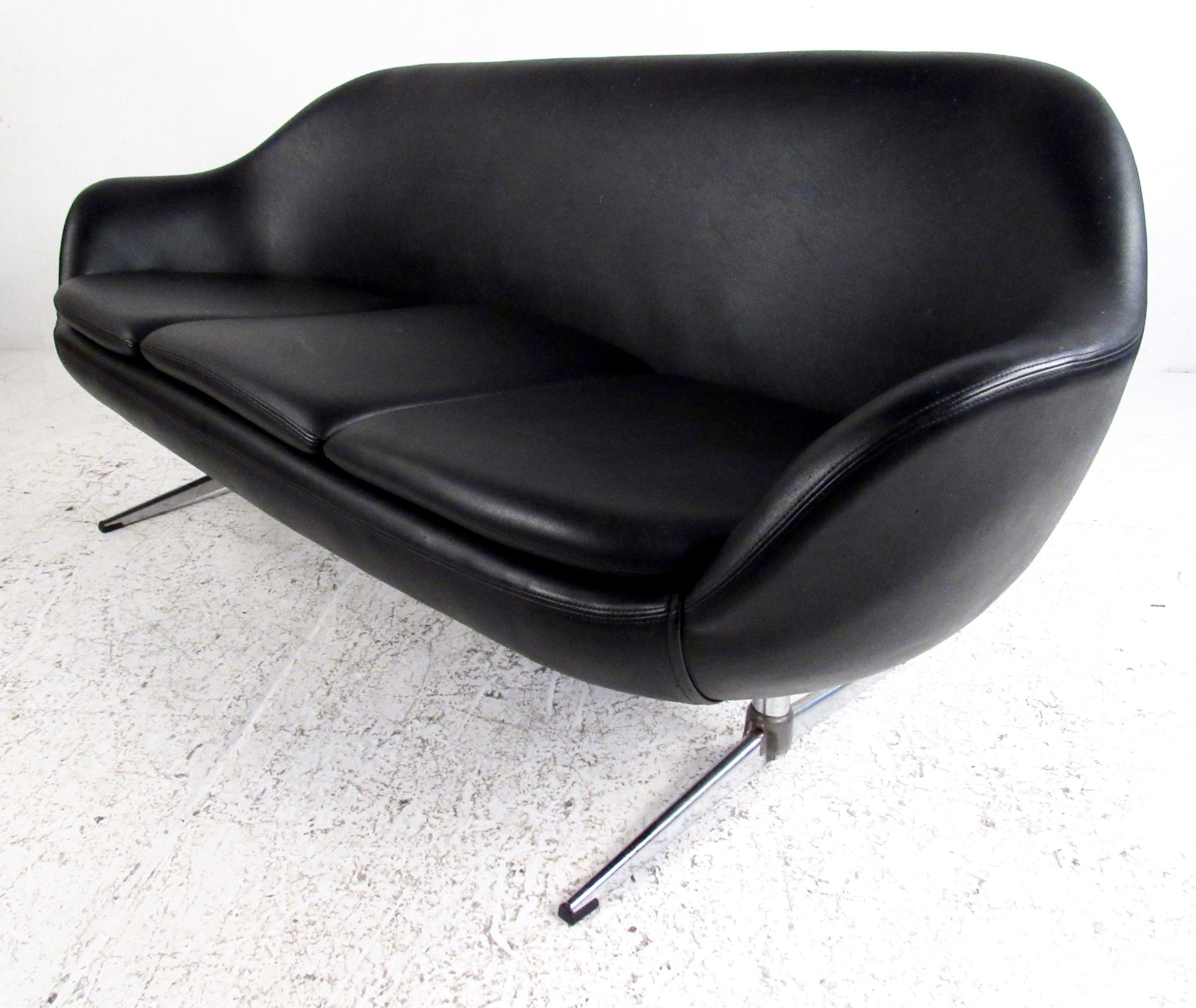 This three-seat pod sofa features stylish sculpted modern seat back, black vinyl upholstery, and unique aluminium base. Sleek Mid-Century Modern style adds to the retro appeal of the sofa, making it the perfect addition to home or business interior.