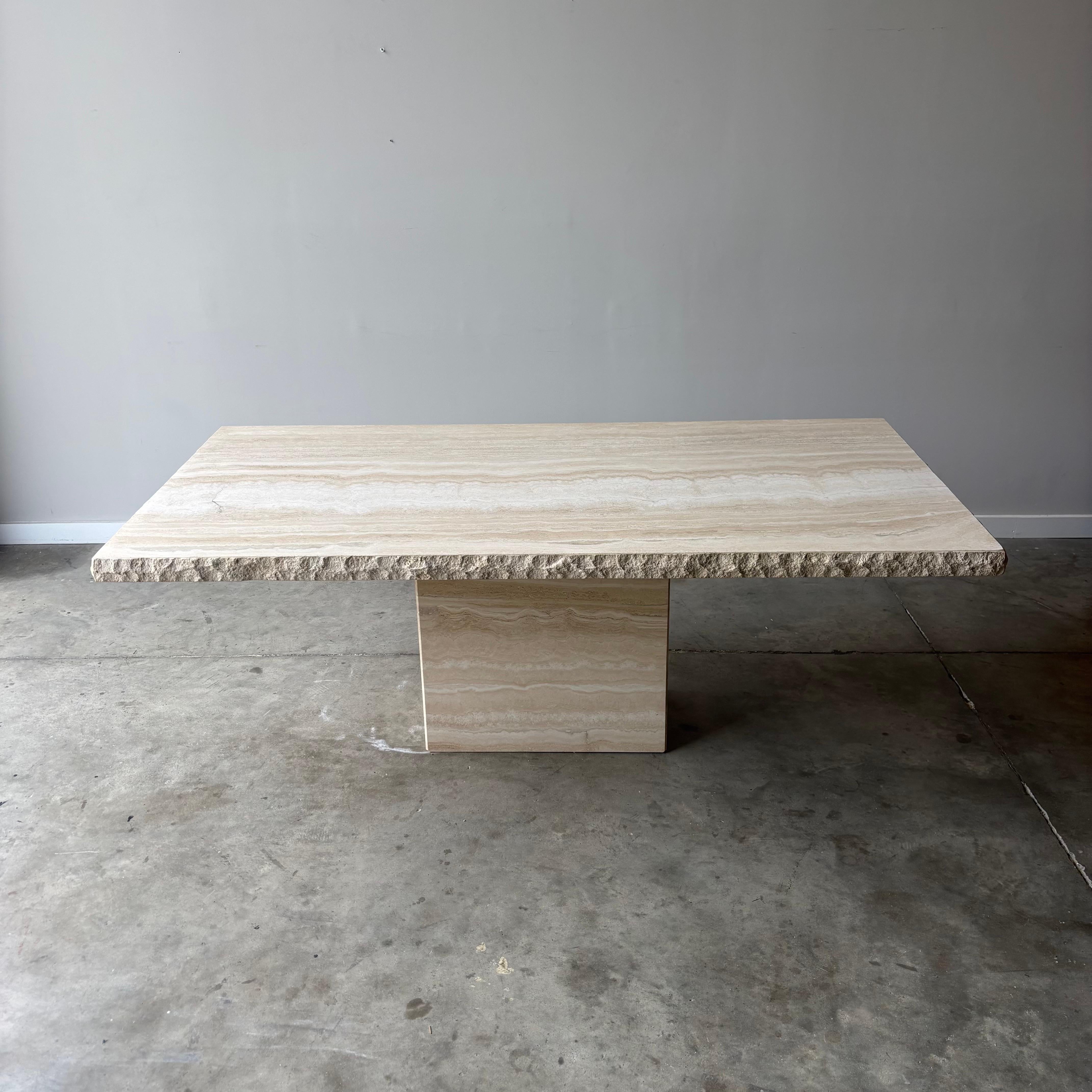This quarry edge travertine table has a minimalist quality to it given the simplicity of the material. The exposed table top and the base are smooth. The table top has a quarry edge, beautifully blending the two textures.  Measuring at 80