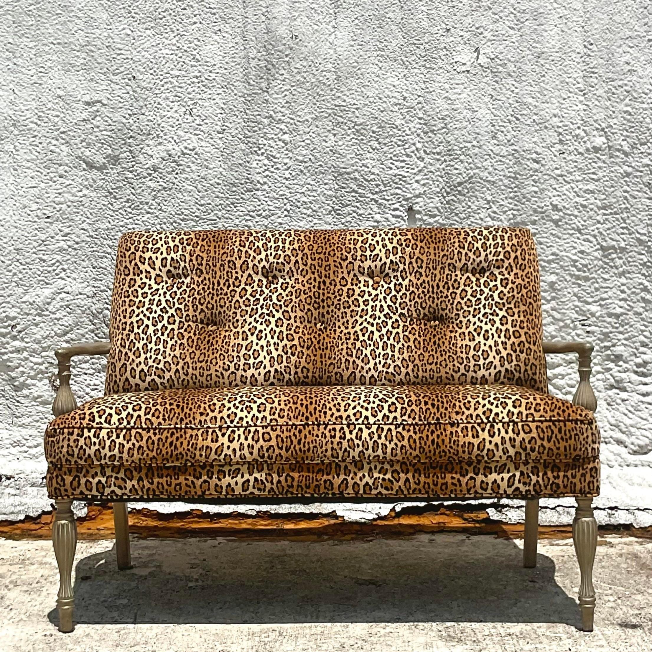 A fabulous vintage Boho settee. A chic leopard upholstery with tufting. Hand carved frame in a vintage finish. Acquired from a Palm Beach estate.