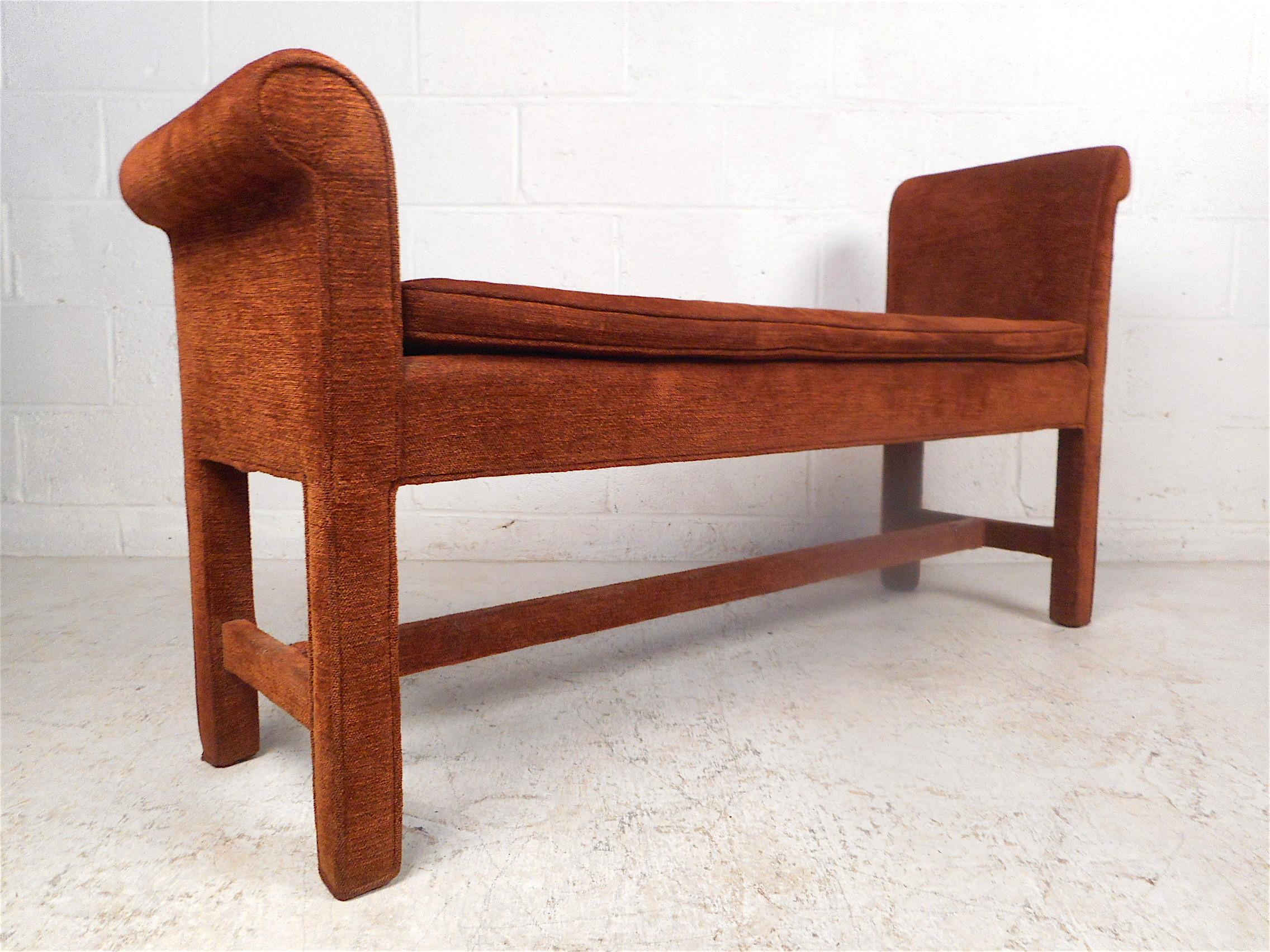 Stylish midcentury upholstered bench. Unusual design with off-set armrests on either side. Covered in a vintage upholstery. Sturdy construction with a stretcher spanning the base. A nice addition to any modern interior, good for use in a