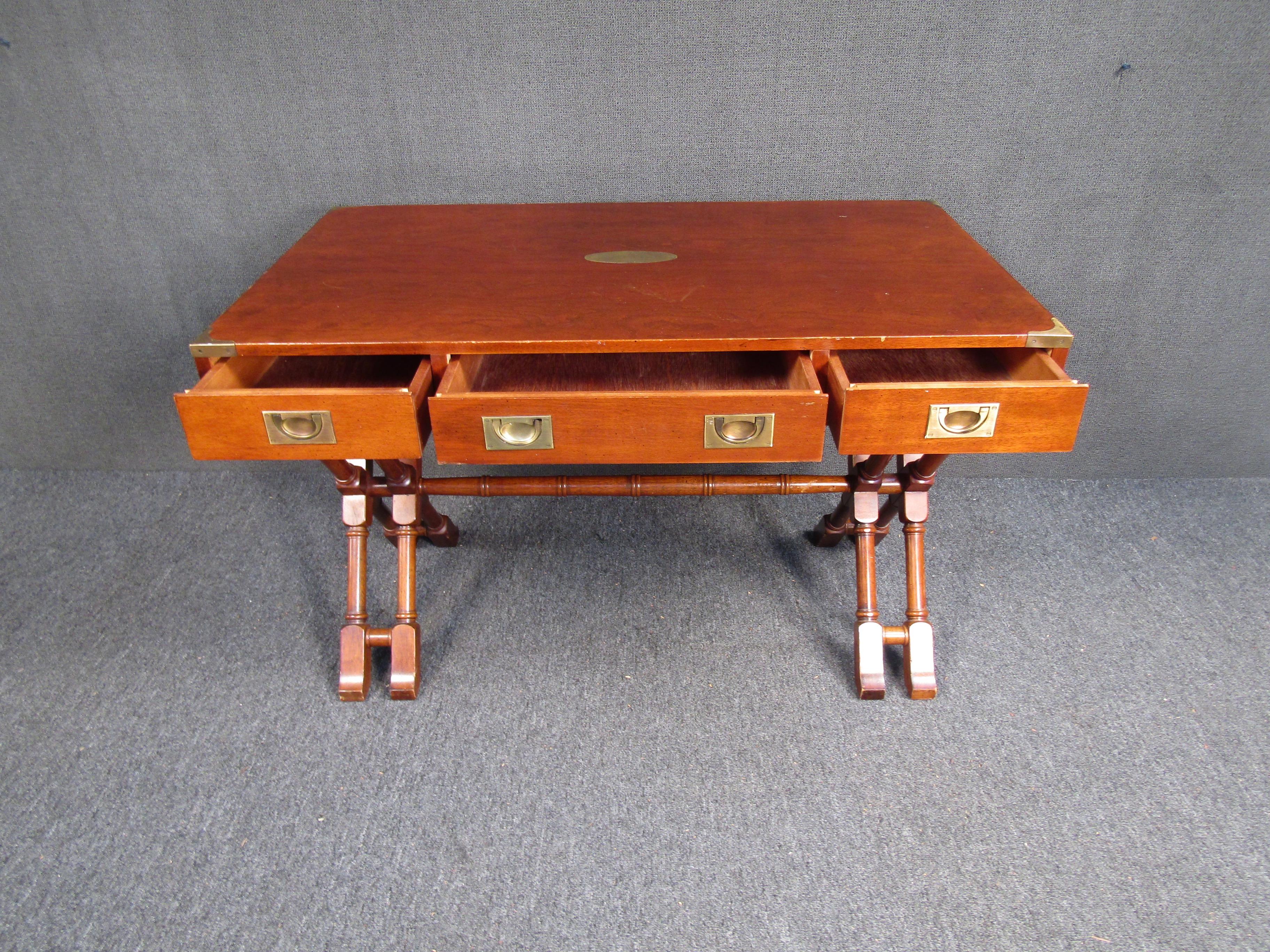 Elegant Mid-Century Modern walnut desk featuring wooden cross legs, brass drawer pulls, and brass accents. The gorgeous walnut grain is highlighted against the brass fittings, making this a stunning piece for any home or office. 

Please confirm