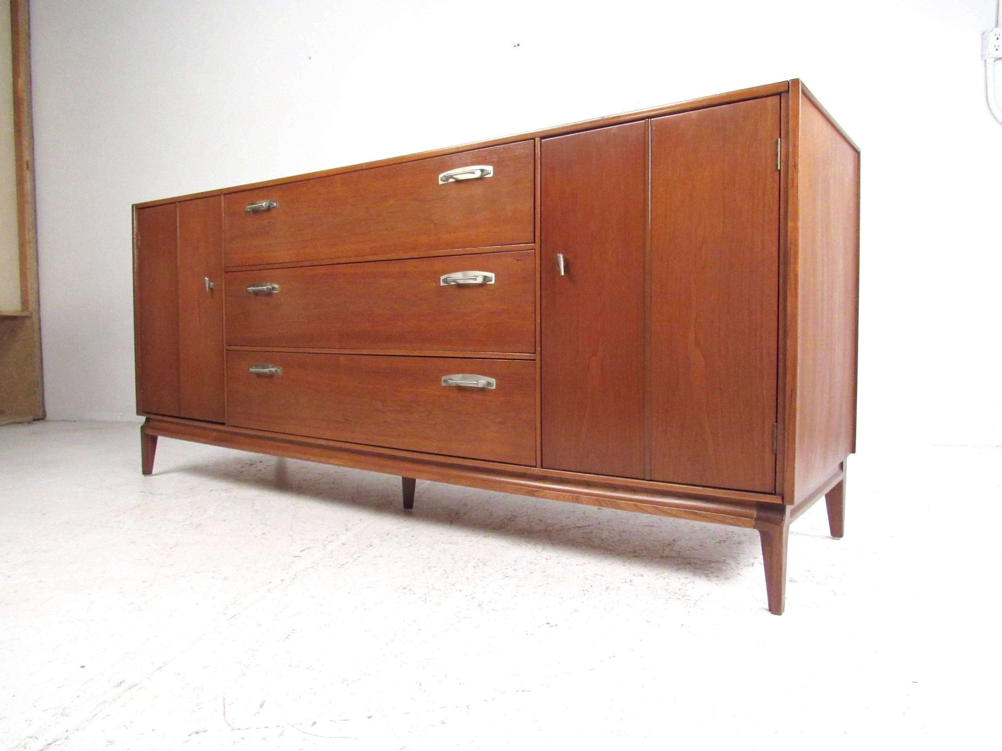 This vintage modern sideboard by J.B. Van Sciver offers spacious storage and unique midcentury style. Distinctive metal door/drawer pulls compliment the rich natural tone of the vintage walnut finish. Perfect storage sideboard for dining room or