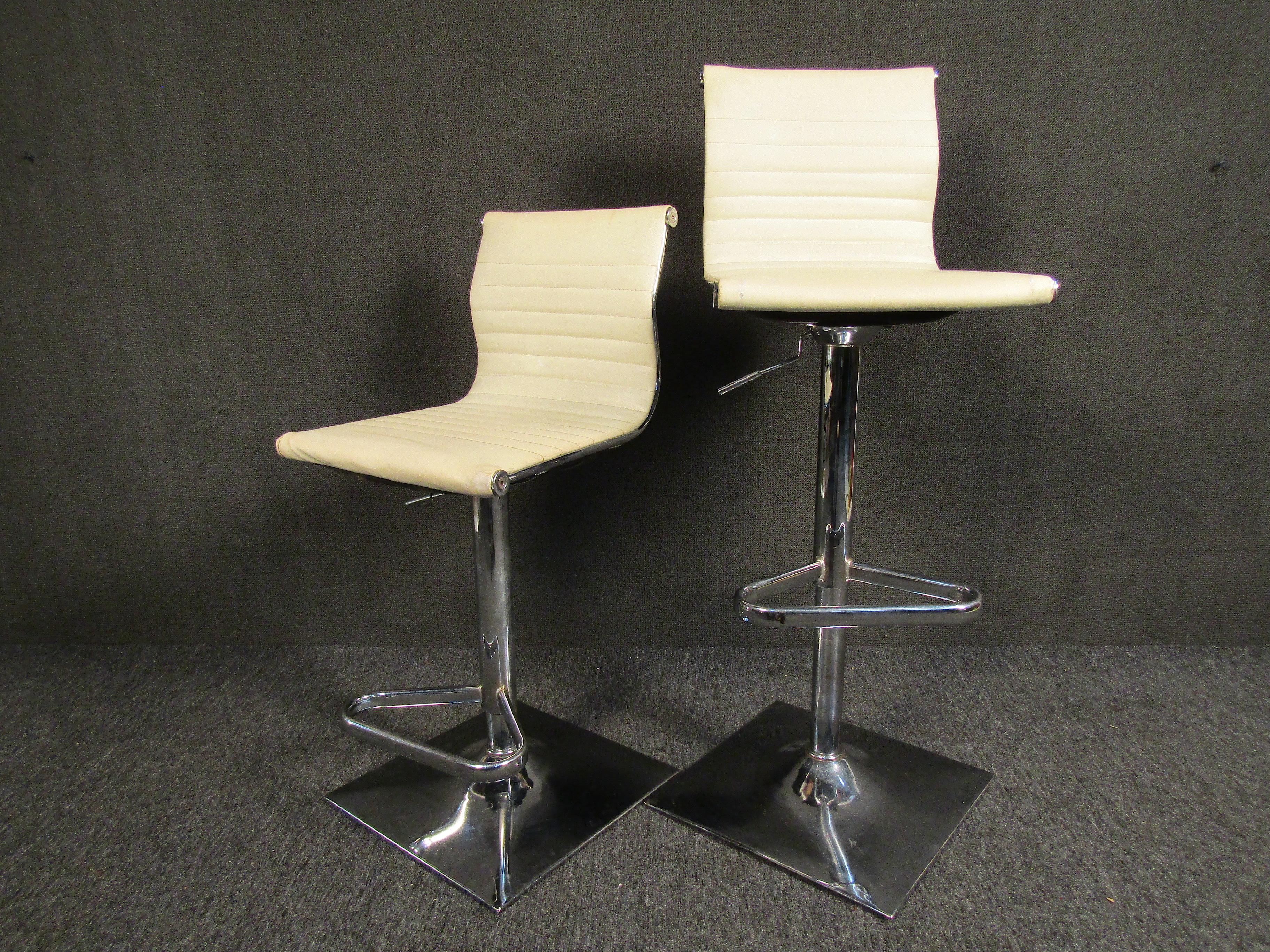 Sleek pair of vintage modern bar stools with adjustable seats. Finished in a white automotive-style vinyl upholstery with chrome footrests and base. These would be a great addition to any bar or elevated countertop.

Please confirm item location