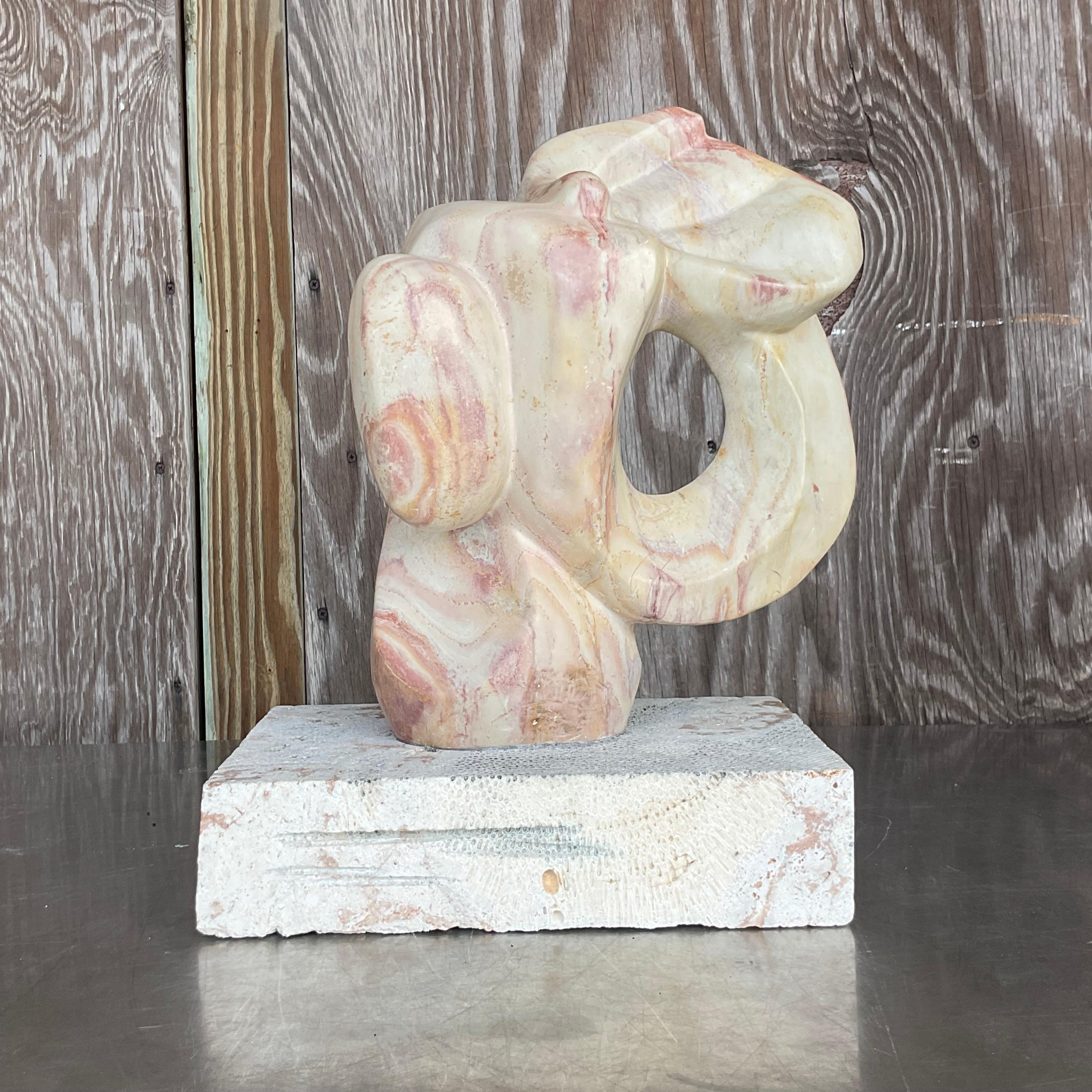 Elevate your space with a captivating blend of artistic prowess and natural beauty. This vintage modernist abstract stone sculpture, elegantly perched atop a coquina plinth, commands attention with its striking form and timeless allure. Crafted with