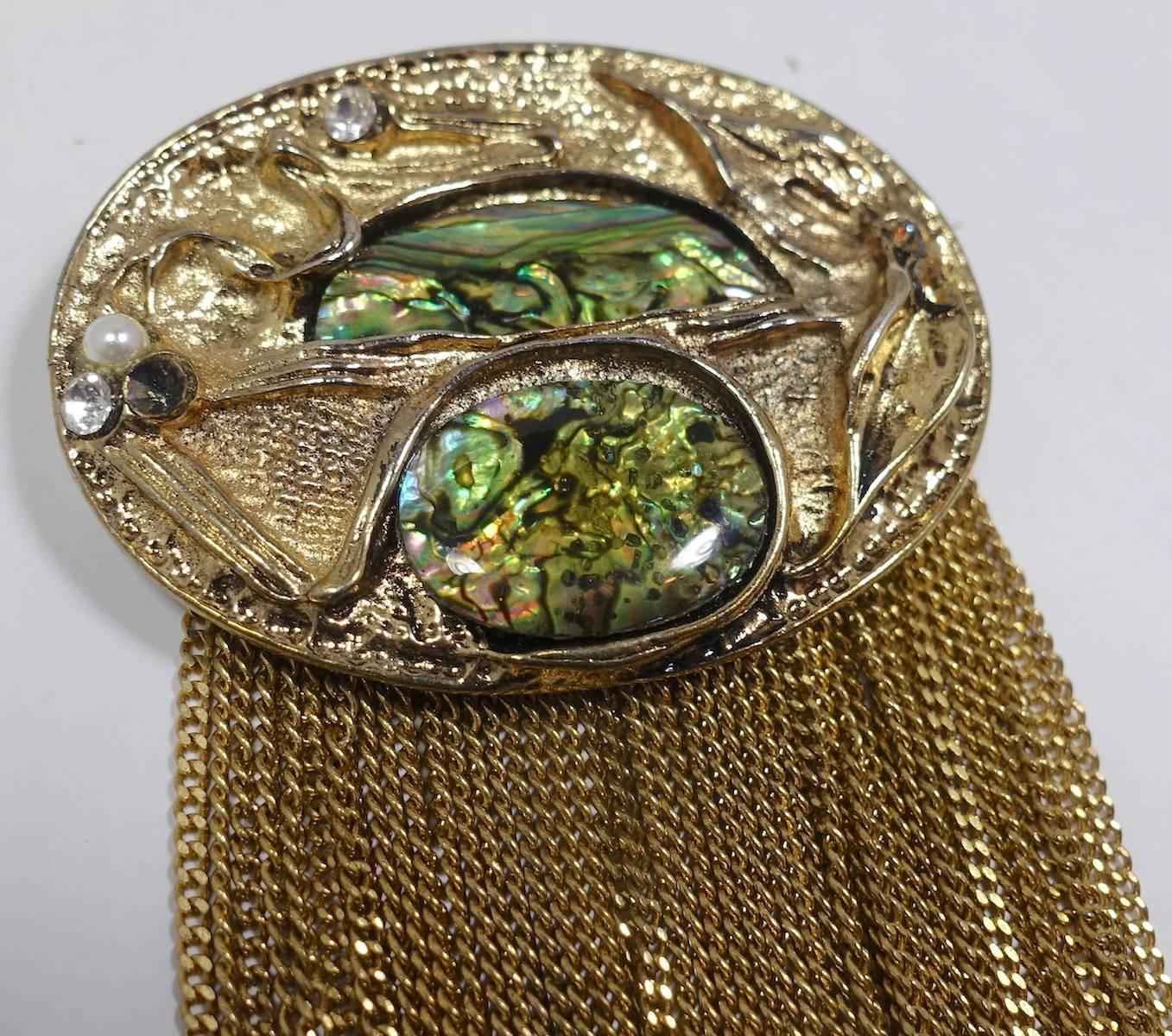 This stunning brutalist design brooch features abalone accents with gold tone chain tassels in a heavily carved bronze tone metal setting.  In excellent condition, this brooch measures 3-5/8” x 2” with a c-pin closure.