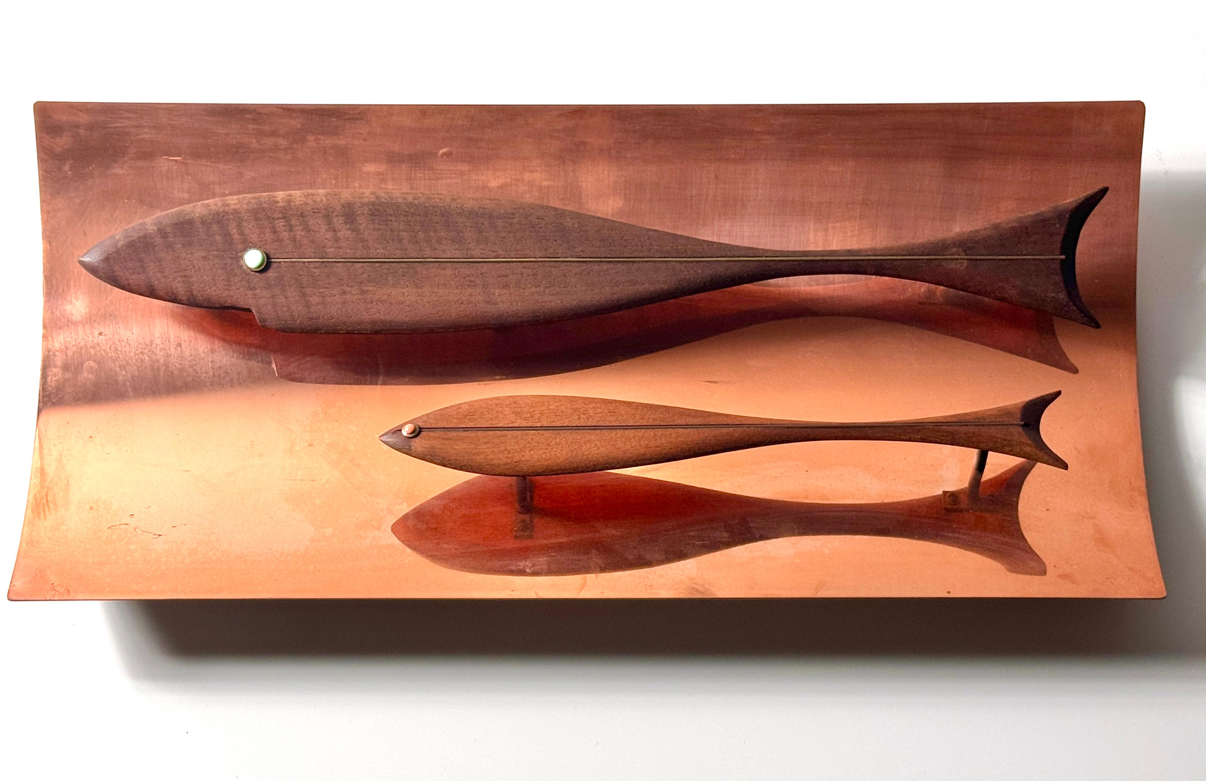 A rare wall sculpture by Westwood Chadwick Studio NJ circa 1970s

Pair of modernist wooden fish with inlaid brass detail and enamel eyes
Mounted and raised from a convex reflective copper surround
Wire hung with original label intact 

24 inch