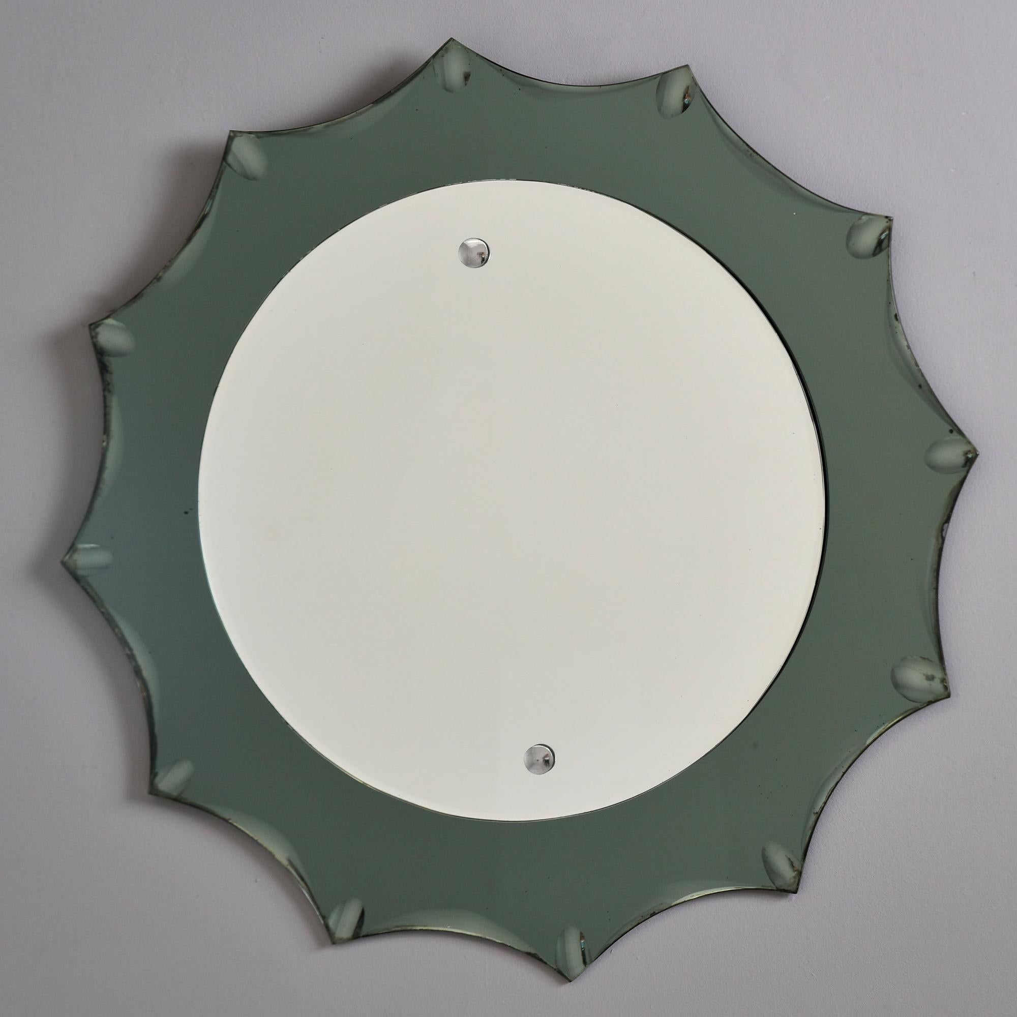 Trouvé en Italie, ce miroir en forme d'étoile encadré de verre date des années 1960. Le cadre en verre de couleur gris fumée présente des bords festonnés et un miroir rond monté au centre. Le cadre en verre est en très bon état et ne présente pas