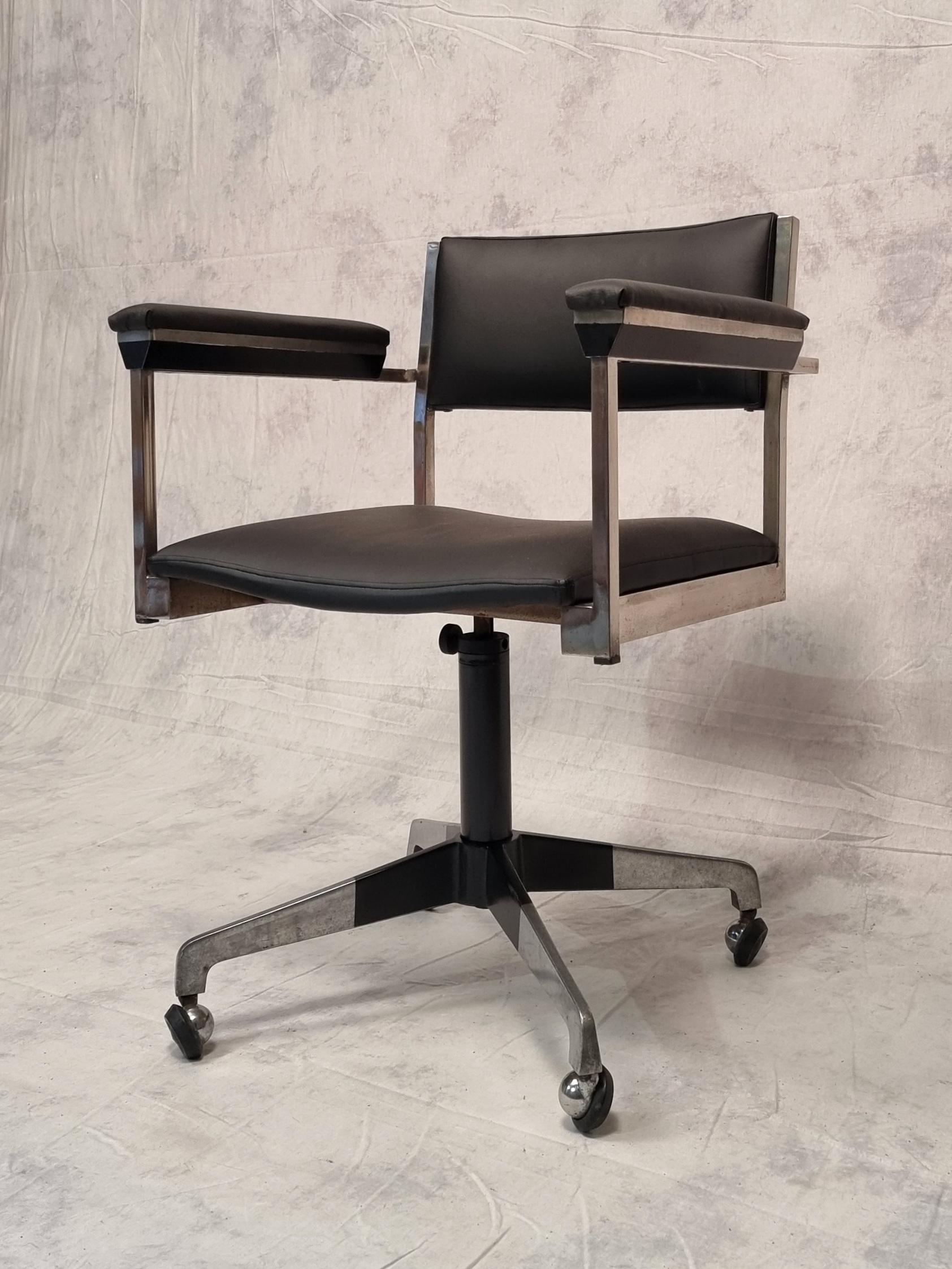 Vintage rotating modernist office chair. German work from the 1960s. Structure in chromed metal and painted black at the base and armrests and upholstered in black imitation leather. Original model with high armrests. A beautiful harmony of colors