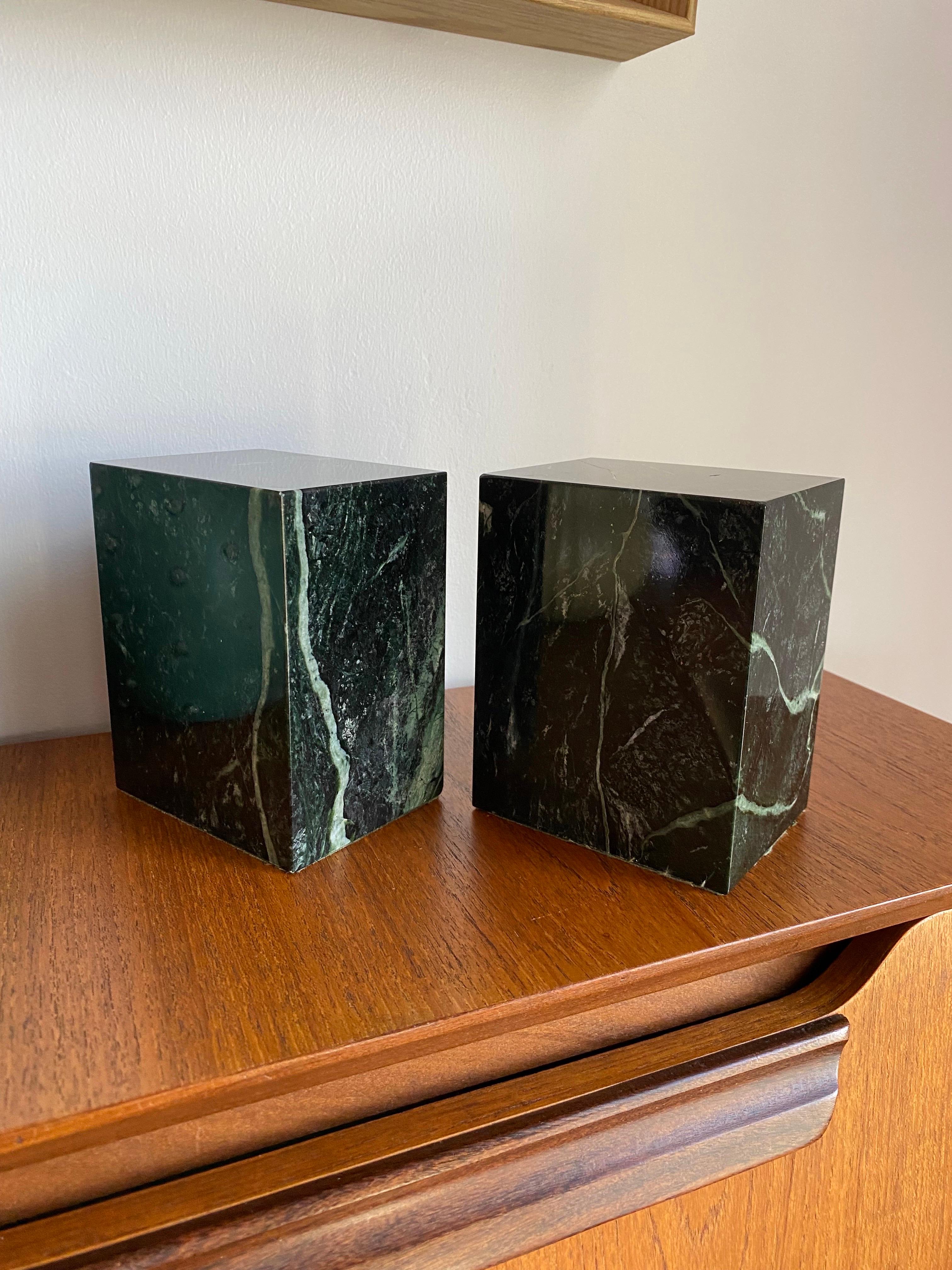 Beautiful pair of modernist marble bookends by Vermont Marble Company. These sizeable pieces of marble are captivating as they are commanding. The veining that develops on the black marble  with green undertones ondulates as the shape forms columns