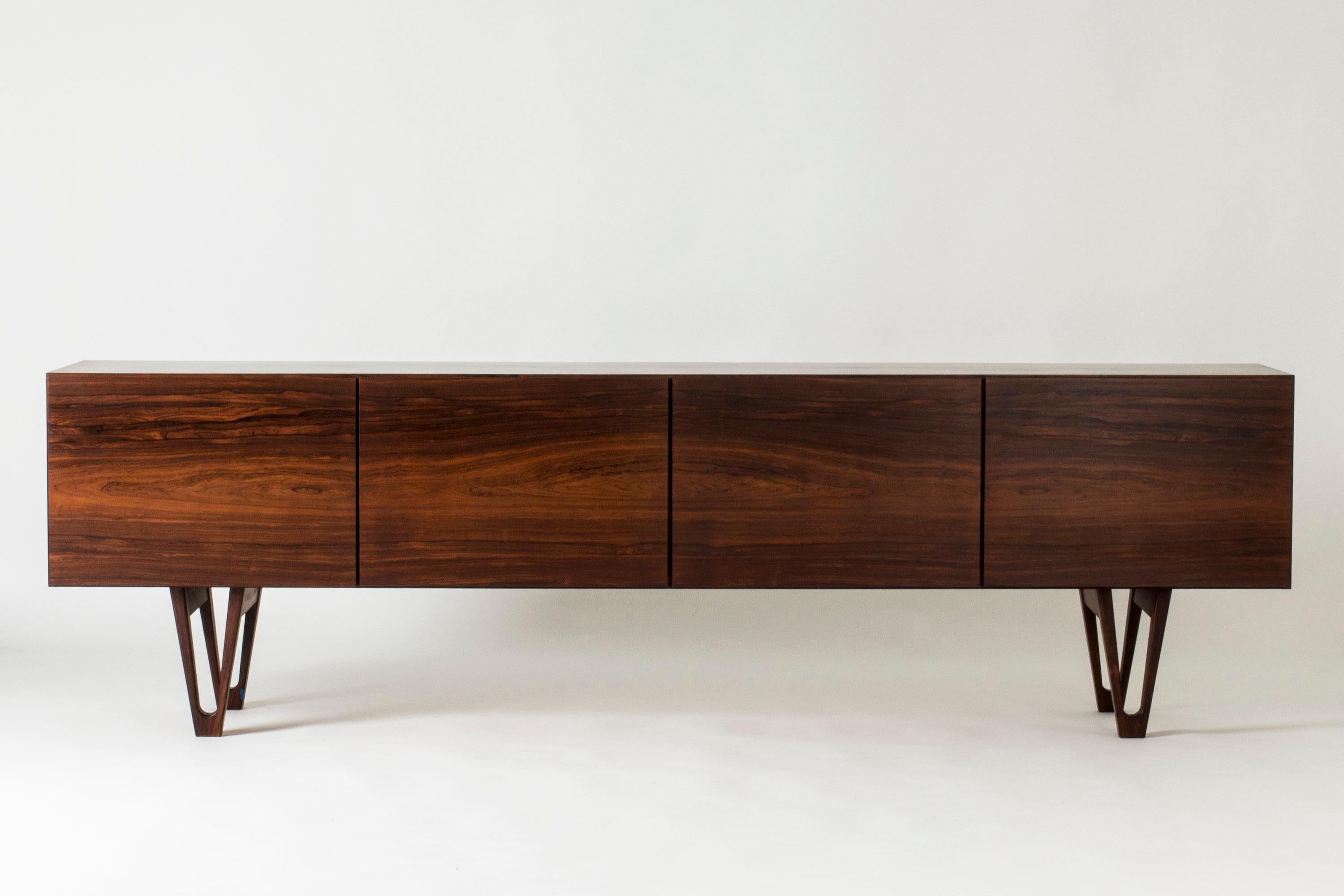 Stunning rosewood sideboard by Ib Kofod Larsen for the Swedish firm Seffle Möbelfabrik. Low design that gives the impression that the sideboard is extra long. Beautifully sculpted legs and carefully hollowed out discreet handles. White drawers