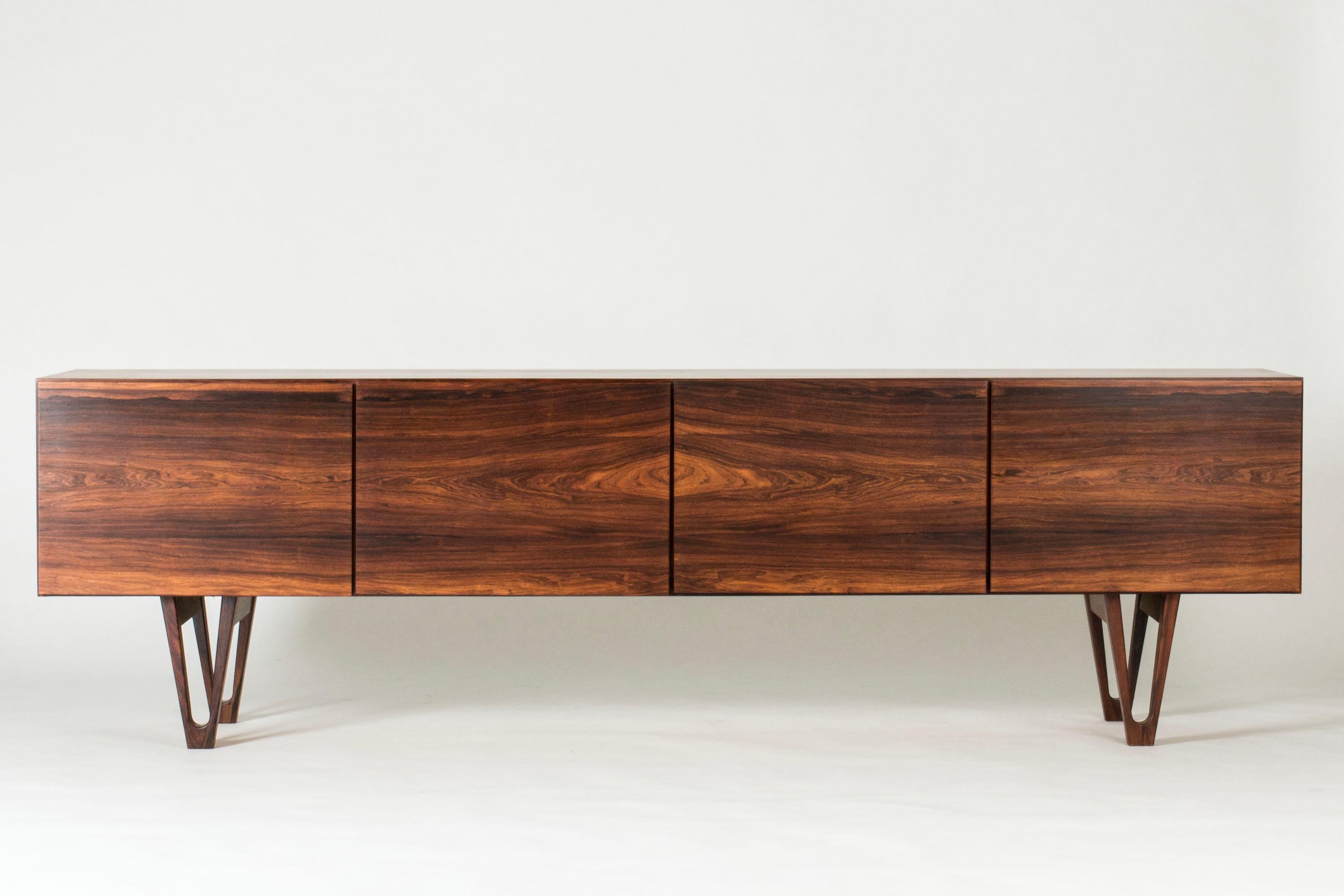 Stunning rosewood sideboard by Ib Kofod Larsen for the Swedish firm Seffle Möbelfabrik. Low design that gives the impression that the sideboard is extra long. Beautifully sculpted legs and carefully hollowed out discreet handles. White drawers