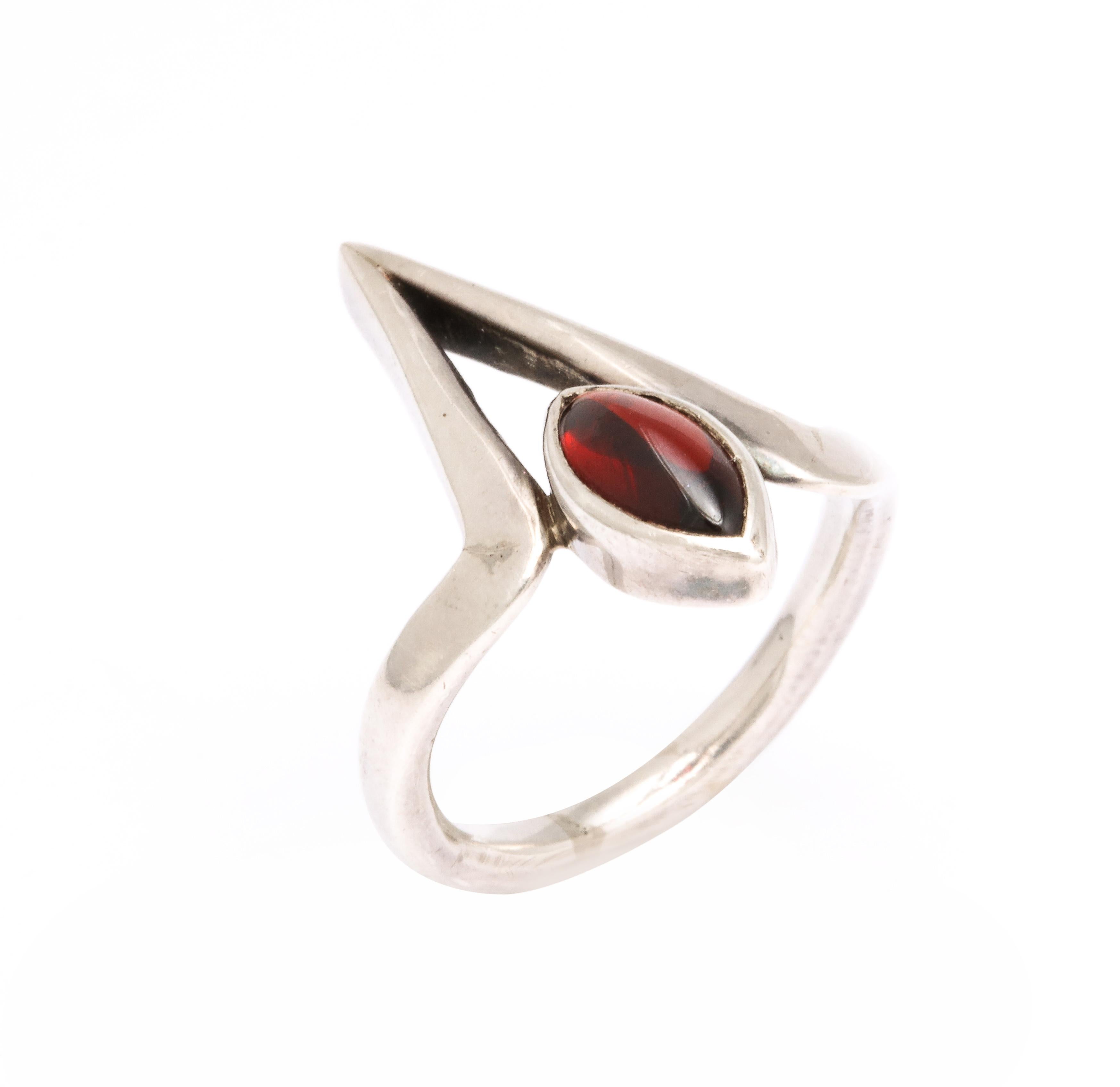We offer a striking asymmetric ring design in silver and garnet made by Jack Nutting, a modernist sculptor and jewelry designer. The oval garnet, deeply set in a substantial silver collet, rests with grace in a triangular pagoda. The ring is one
