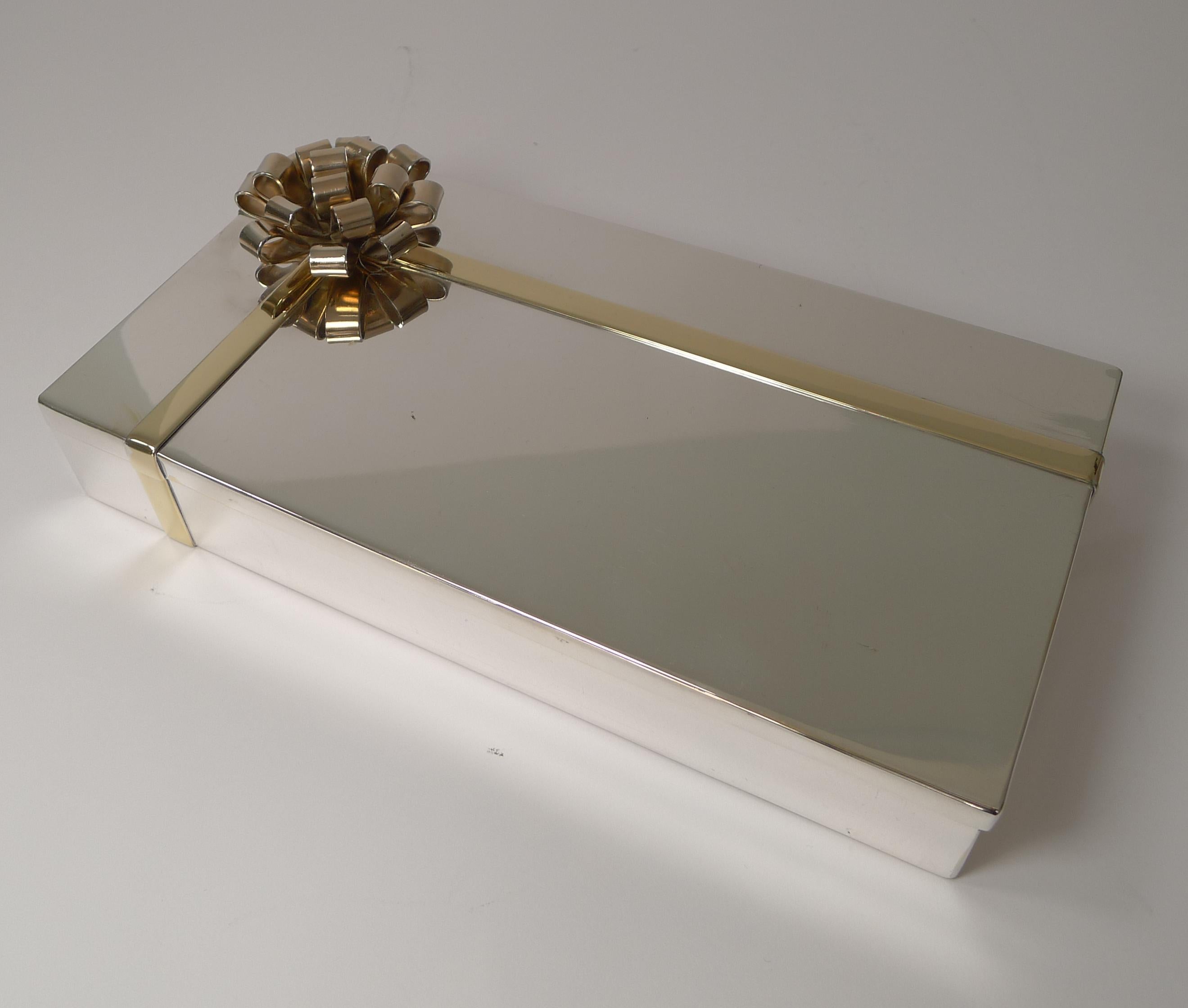 A lovely quality modernist box that came to us looking a little tired but has been beautifully restored in our silversmith's workshop to it's former glory.

A good weight box in silver plate, the ribbon gilded with yellow gold and the bow, more of