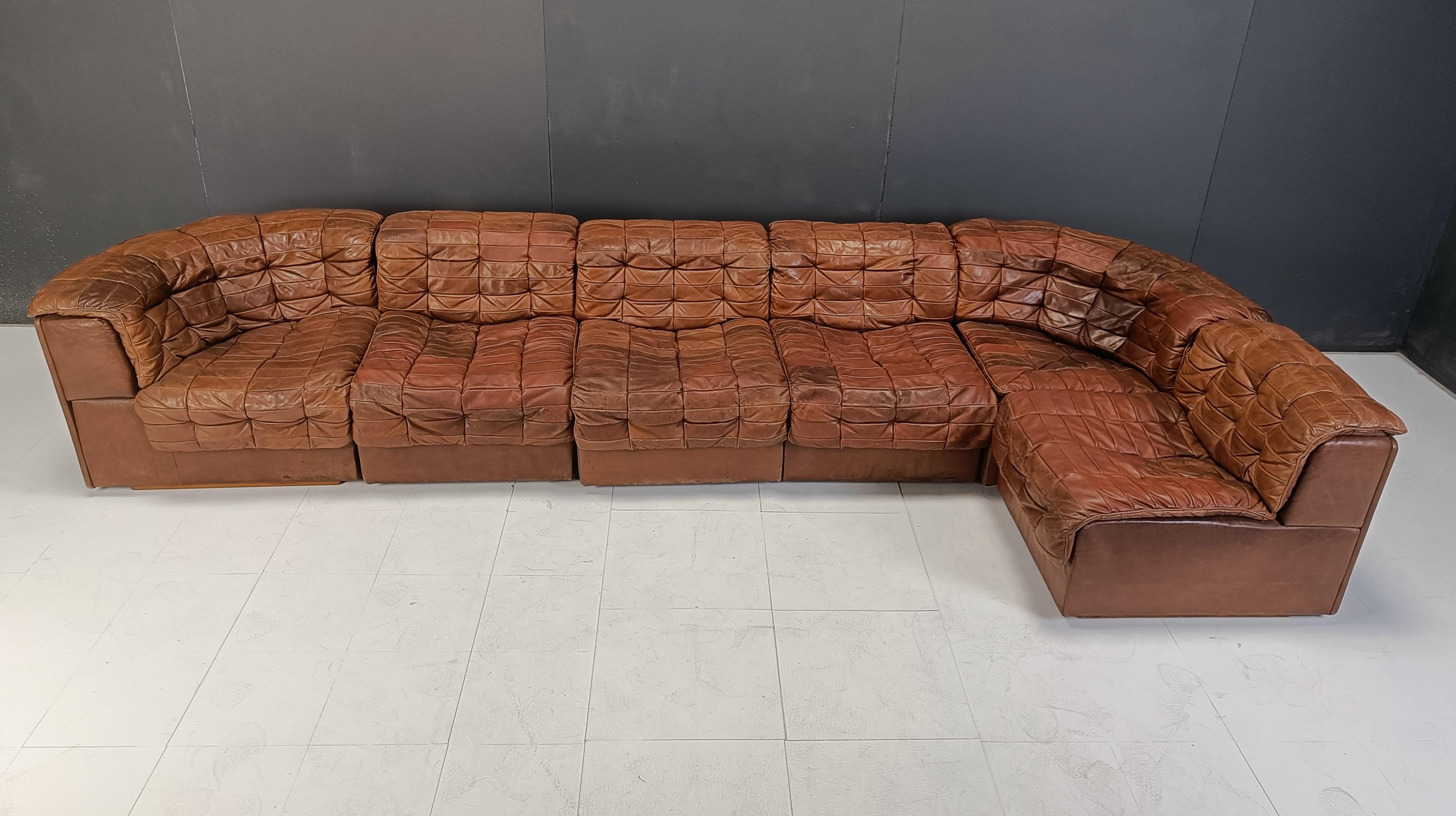 Mid century brown patchwork leather modular sofa by Desede.

Desede produced high quality leather sofas and is still producing today.

This particular setup is great to fill up a living room and comes complete with its rare to find cushions.

The