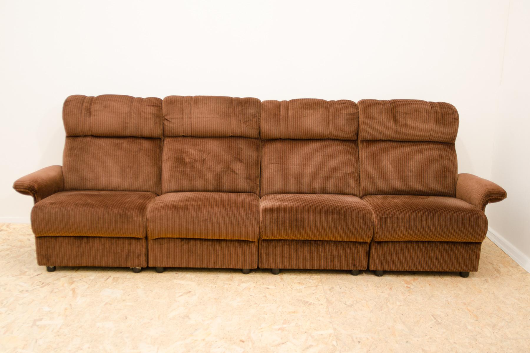 Dieses modulare Sofa wurde in den 80er Jahren in Mitteleuropa, wahrscheinlich in Deutschland, hergestellt. Er kann in 4 freistehende Sessel auf Rädern unterteilt werden. Er ist aus Sperrholz, Schaumstoff, Holz und Polsterung gefertigt und mit