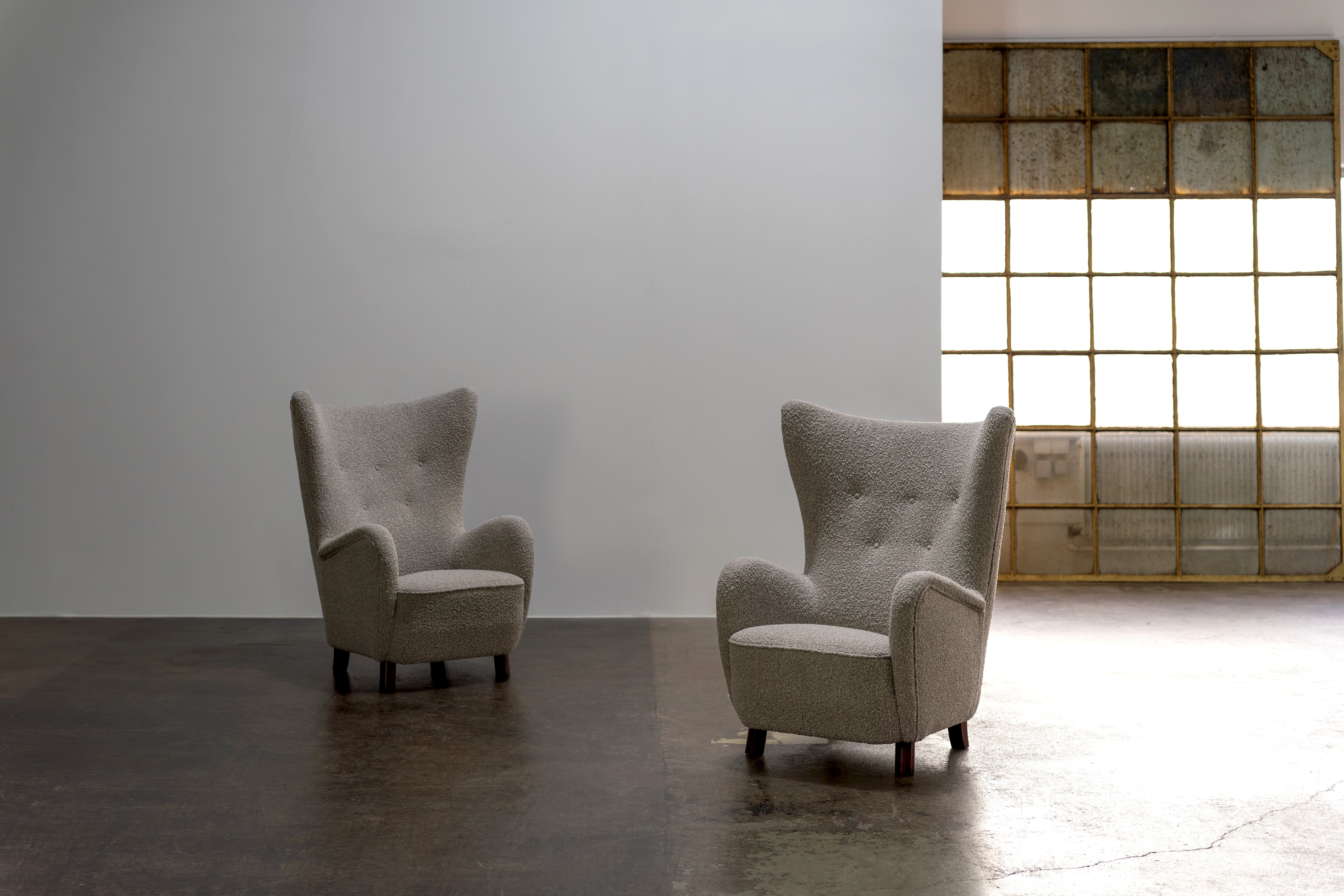 High-back wing chair by Mogens Lassen from the 1940s. These examples were made in the early 50s.
Dark-stained beech wood feet, spring-padded seat and padded back. The upholstery was renewed and the armchair was reupholstered with high-quality boucle