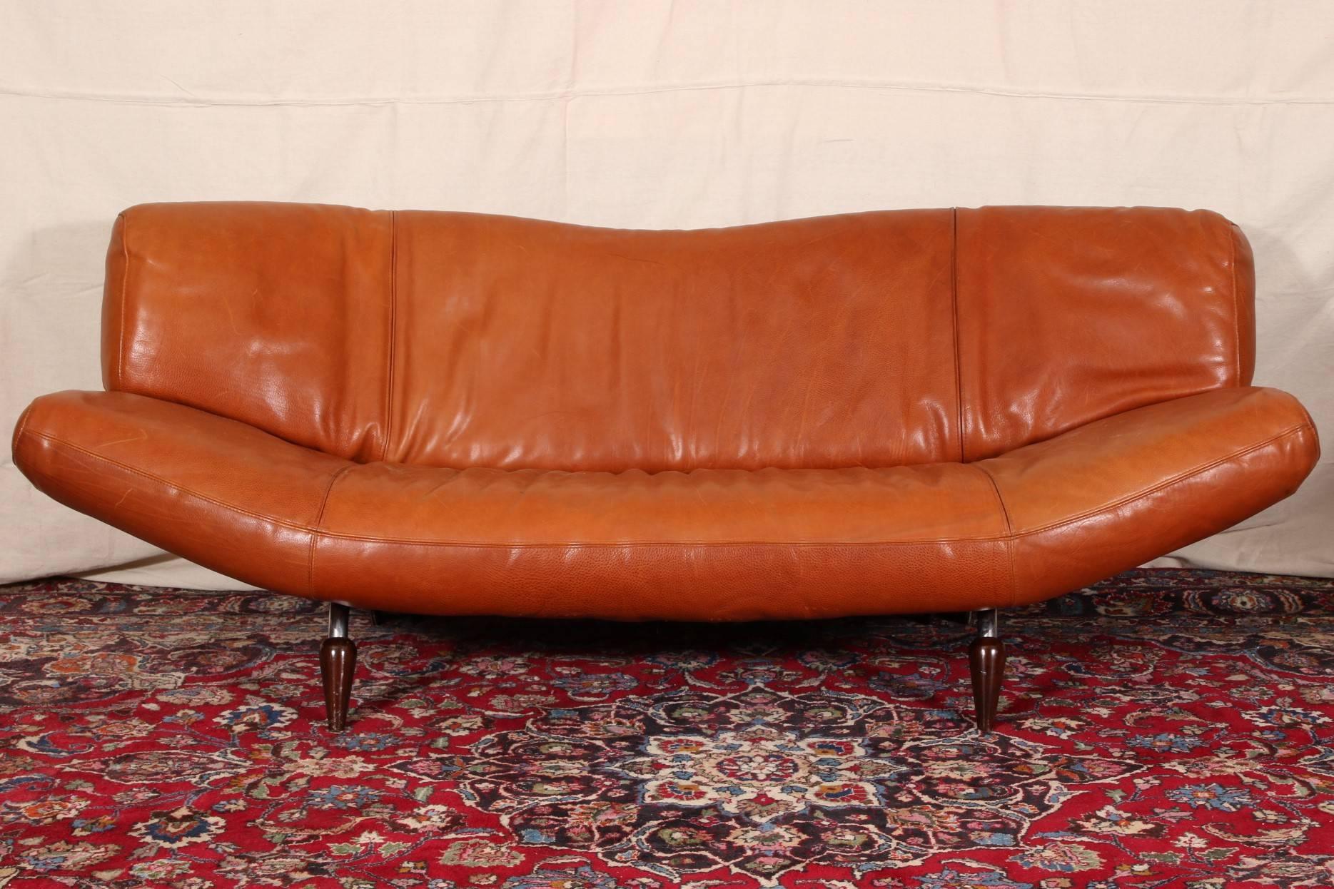 Vintage Molinari tobacco leather sofa, curved back and seat with adjustable arms (the right one does not lock into place when adjusting). Raised on chrome topped dark wood round tapering splayed legs in front and chrome wheeled ones at back.