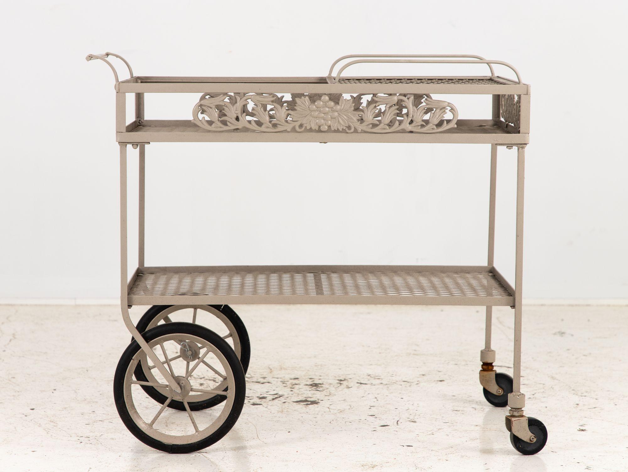 An Aluminum Garden Bar Cart on Casters, boasts a luscious Grape and Grape Leaf Motif, reminiscent of Molla's timeless design. Crafted with precision and finesse, this cart seamlessly combines functionality with style. Its later gray paint on an