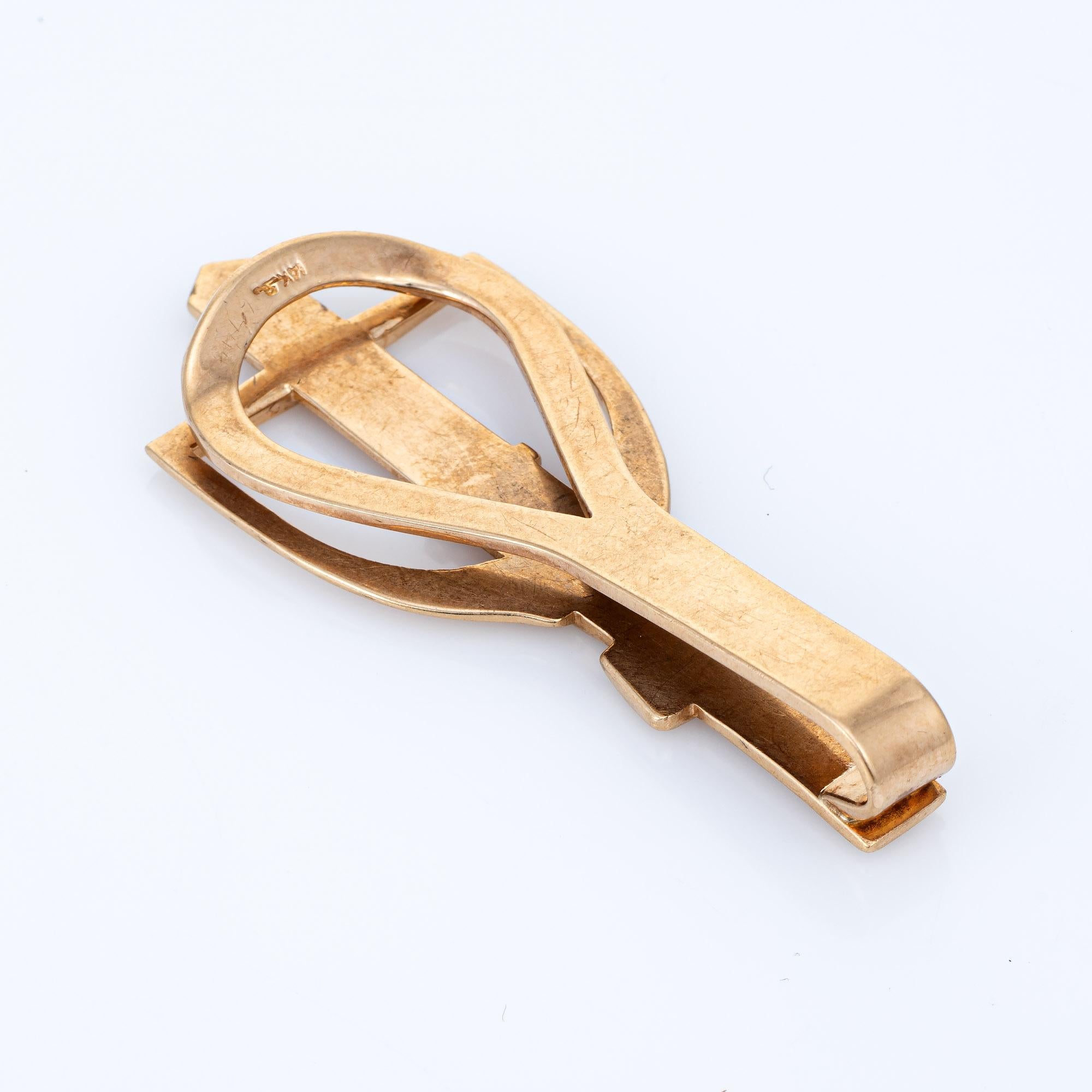 Stylish equestrian themed money clip crafted in 14k yellow gold (circa 1950s to 1960s). 

With a belt looped through the stirrup the horse themed dual-purpose money clip or tie bar is a unique piece for that hard-to-buy-for person in your life. It