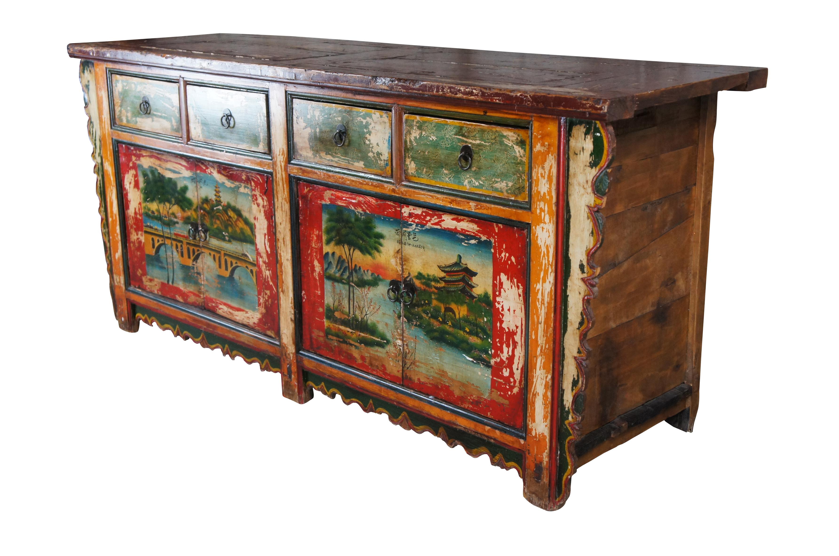 Vintage Mongolian / Chinese sideboard cabinet or console. Made of Elm featuring rectangular form with scalloped accents and four drawers, two cabinets and a painted and lacquered exterior that features the landscape of two cities. 

One side