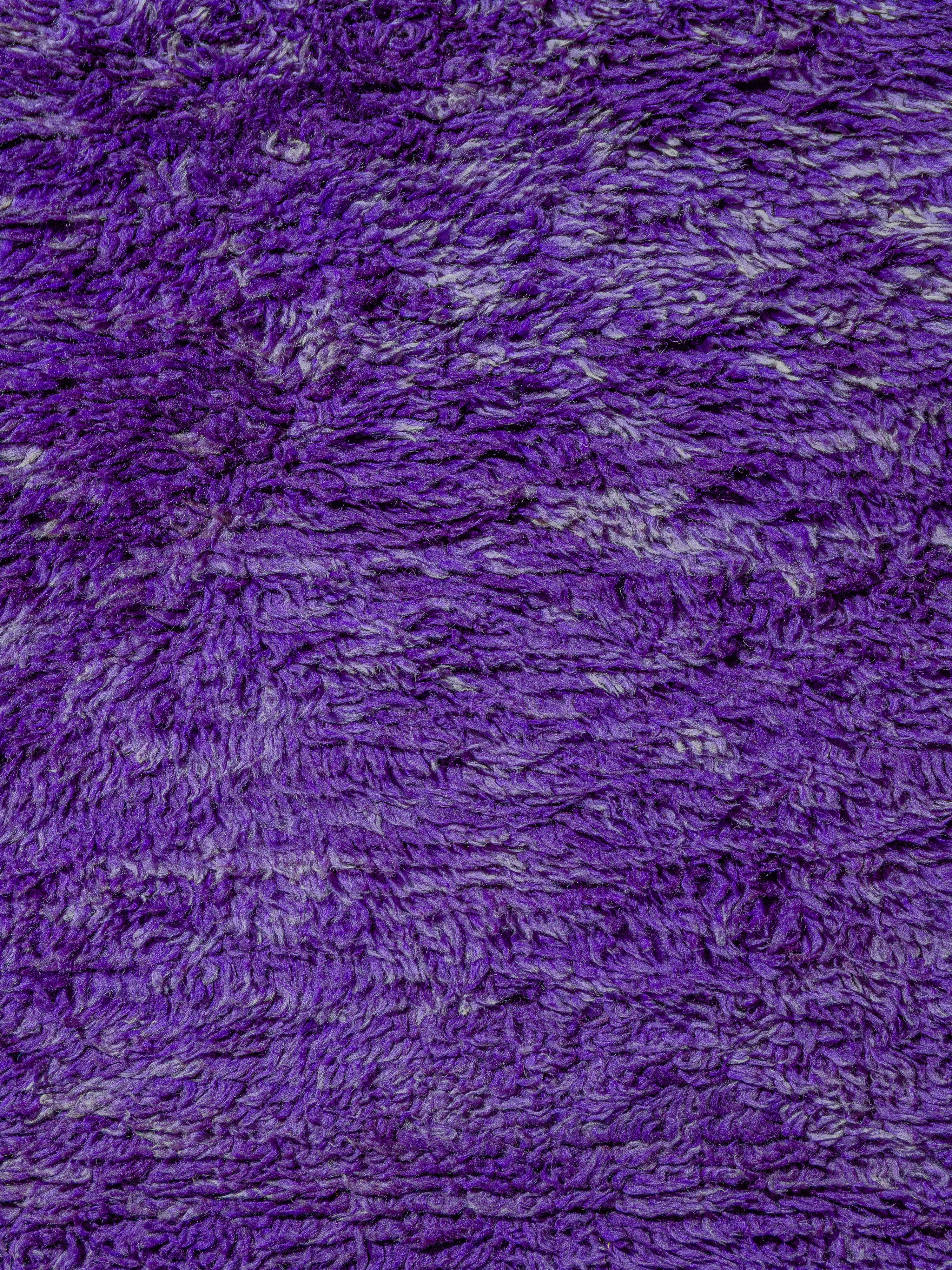 Un tapis marocain vintage monochrome Beni M'Guild aux poils denses, créant une texture luxuriante sous les pieds. Noué dans un violet saturé avec de subtiles variations dans les lots de teinture, créant une dimension et une texture visuelle tout au