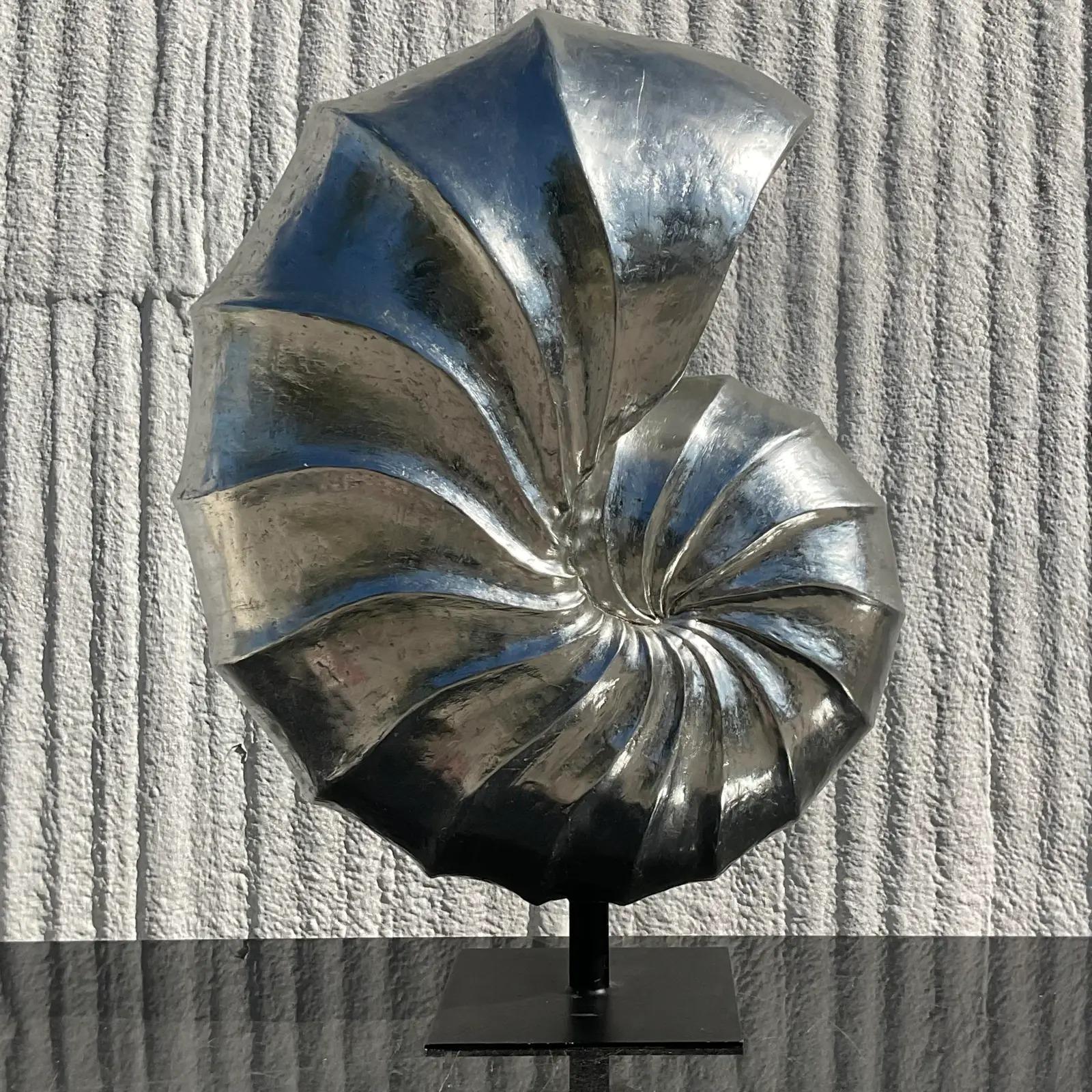 A fabulous vintage Coastal Nautilus shell sculpture. Monumental in size and frame. Beautiful chic design in a silvered resin. Rests on a metal plinth. Acquired from a Palm Beach estate.