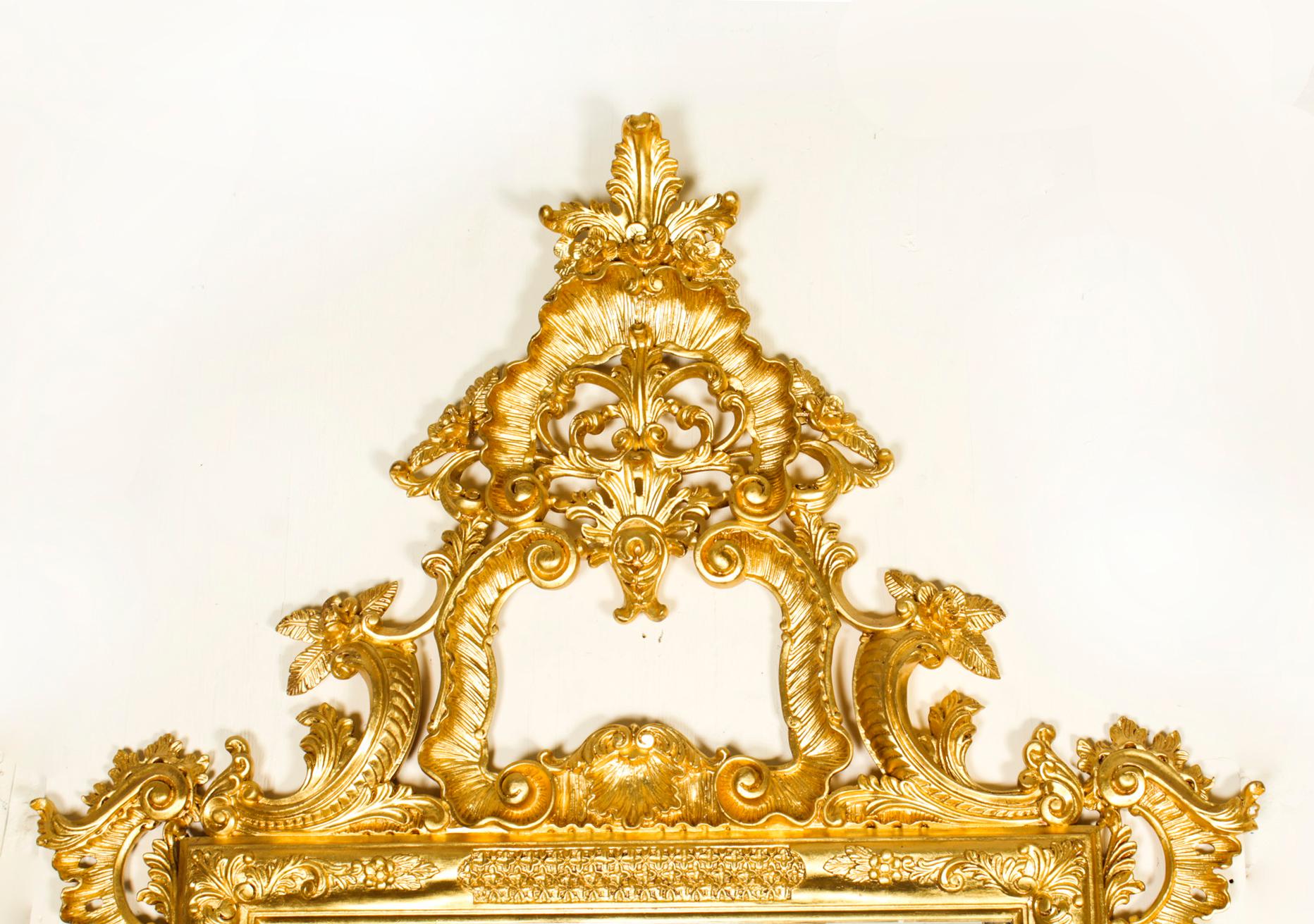 This is a finely hand carved monumental Italian Rococo Revival giltwood mirror, dating from the late 20th century.

It features a large exaggerated central multi directional pieced acanthus leaf cartouche crest. The outset corners have decorative