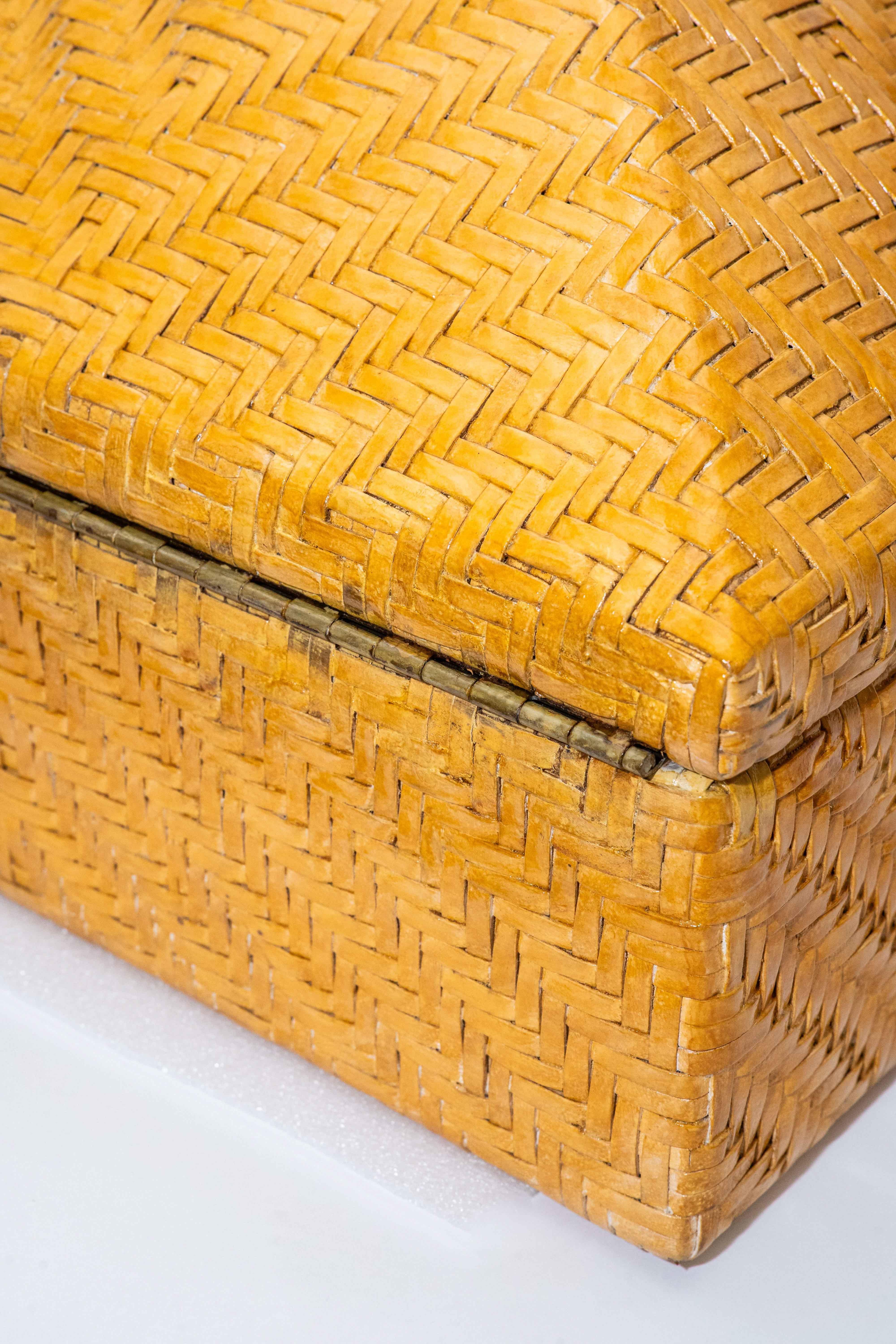 Questa scatola vintage molto grande e monumentale con cerniera e leva in ottone patinato è intrecciata con pelle e legno in un ricco colore dorato. Assomiglia al rattan. Le cerniere e l'apertura in ottone sono state lucidate. È pesante. La forma