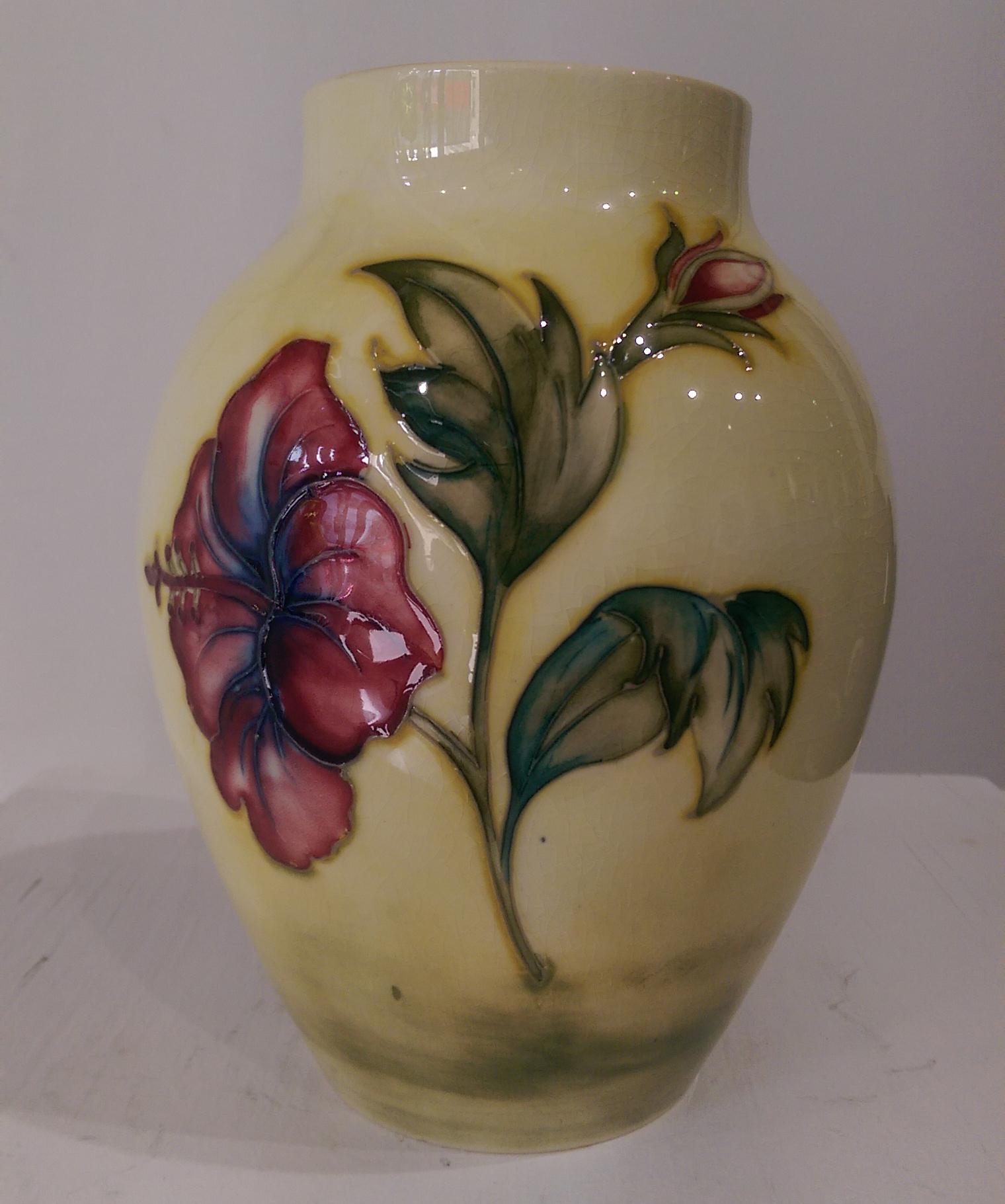 Beautiful vase of Ovoid form is decorated in the much sought after luscious hibiscus flowers in coral, pink, blue and yellow on a field of soft yellow. Measures approximate size: 7.5 inches high x diameter, top 3