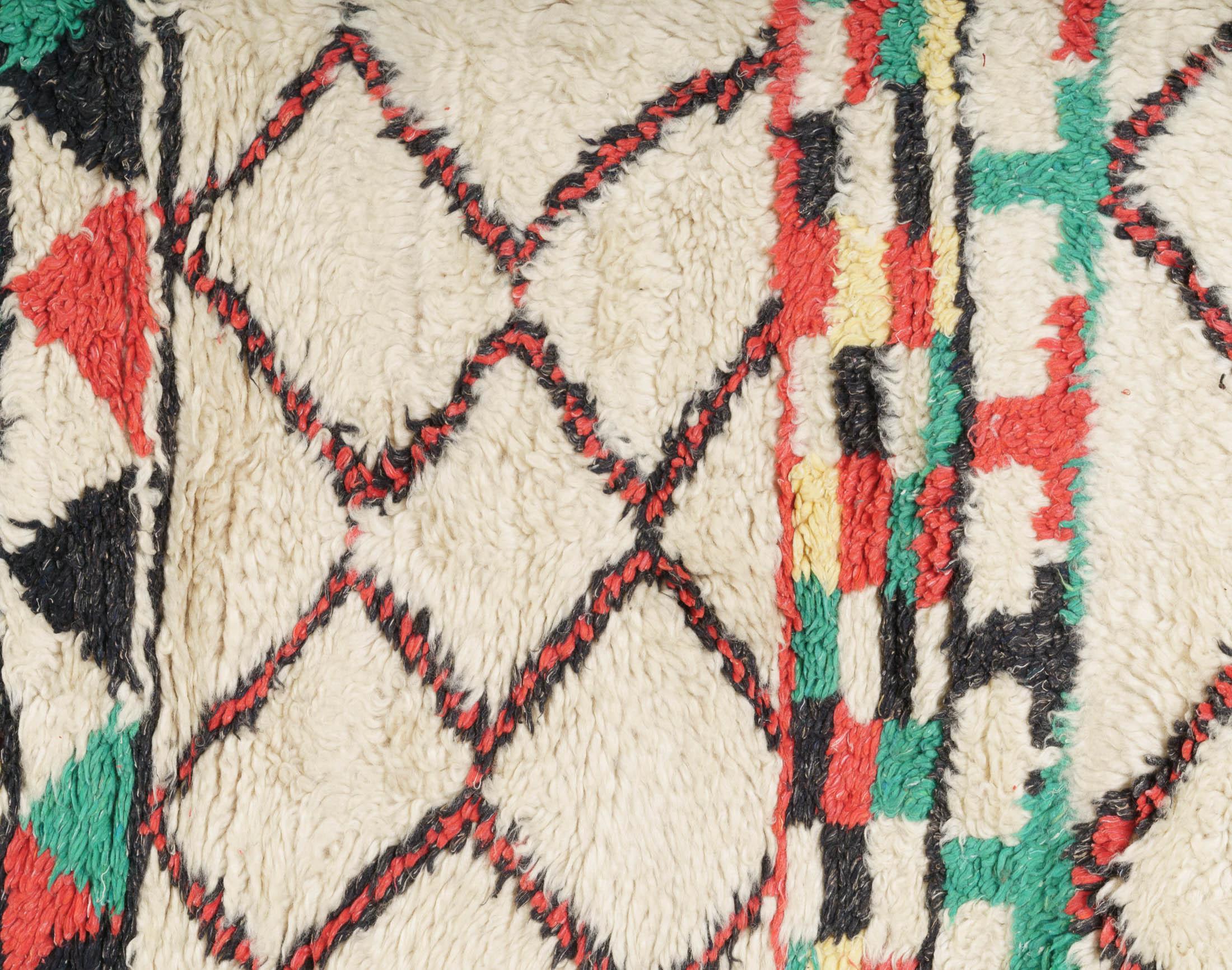 Classical Moroccan Berber rug from the Azilal region. Black, red, yellow and green pattern on natural off-white background. Medium-short pile.

This is an authentic Berber carpet from Morocco. In Berber tribes rugs are hand knotted by women in