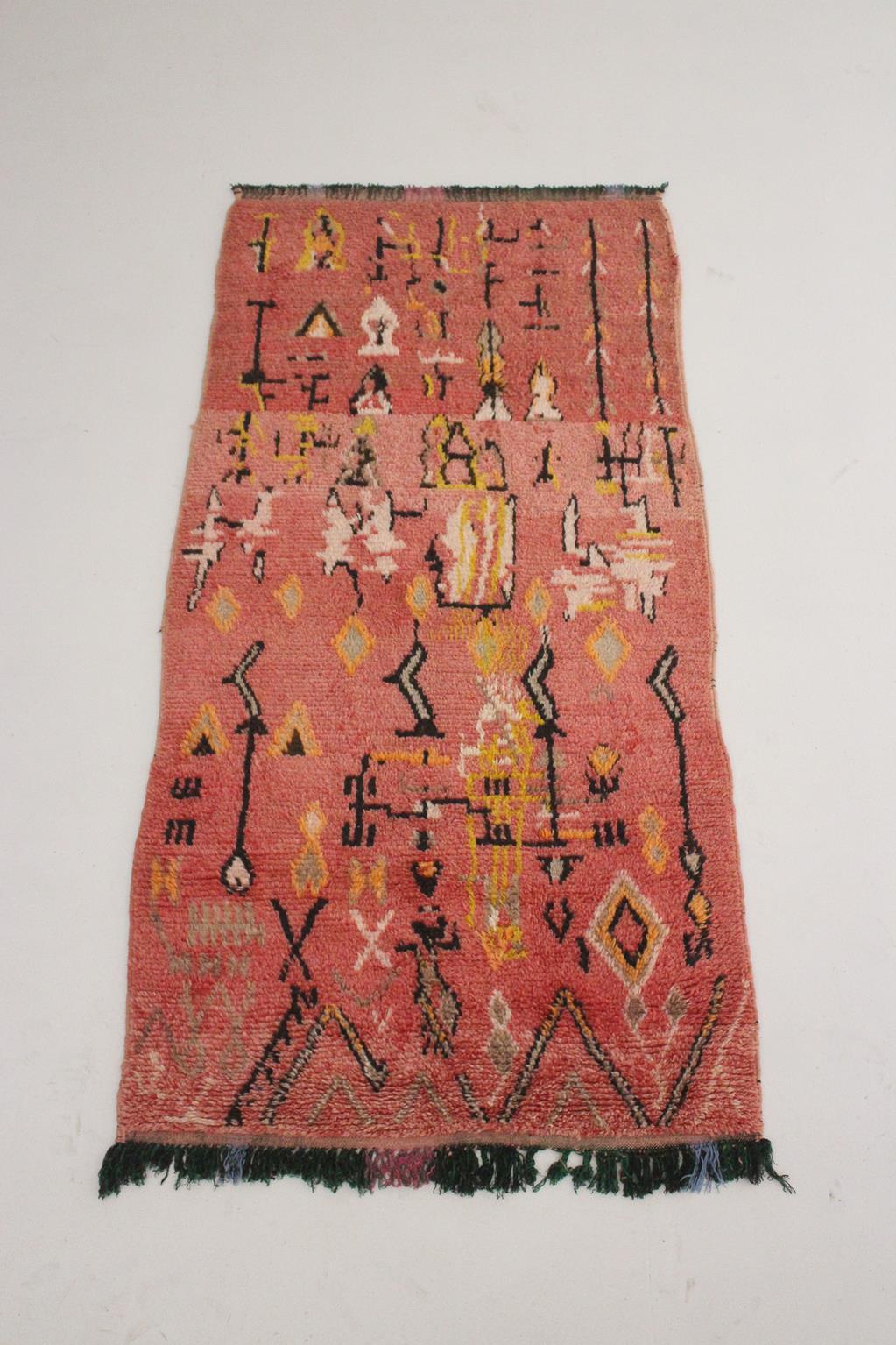 This unique, vintage runner rug was sourced in the area of Ait Bouguemez, Morocco. It is a real vintage Azilal rug with light signs of age but in an beautiful condition overall and unmatched quality. The main background color is a pink with yellow,