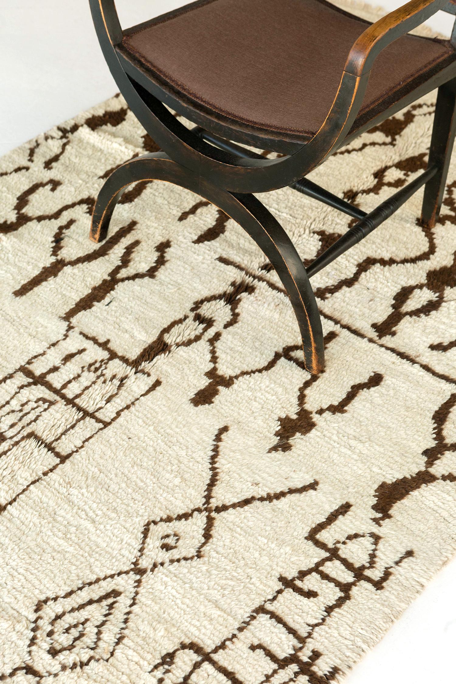 Fancify your room with our Azilal Tribe Moroccan rug from Atlas Collection. It highlights the hazel-outlined chevrons, eye, diamonds, lozenges with extended sides, zigzags, and other ambiguous Berber symbols in an off- white field. A centerpiece