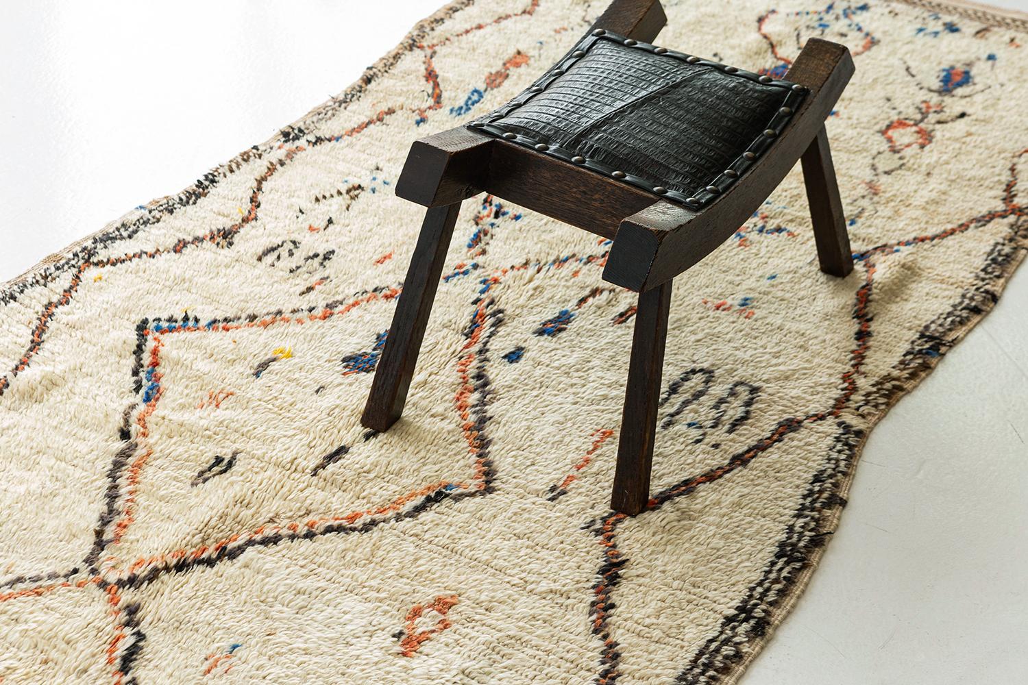 Ivory pile rug with mercurially drawn diamond and zigzag designs and archaic motifs in brilliant azure, apricot and natural brown. A unique vintage tribal rug from the Atlas Mountains of Morocco.