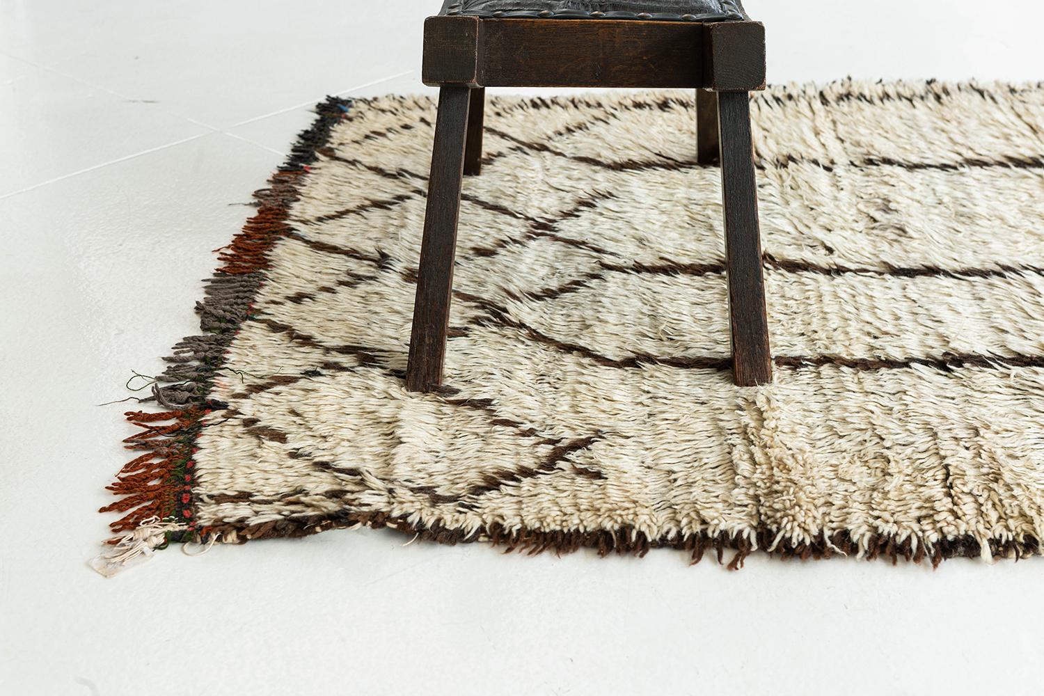 Deep ivory pile with a dark brown linear motif of diamonds and vertical divisions. Subdued color in the fringe. A unique vintage tribal rug from the Atlas Mountains of Morocco.