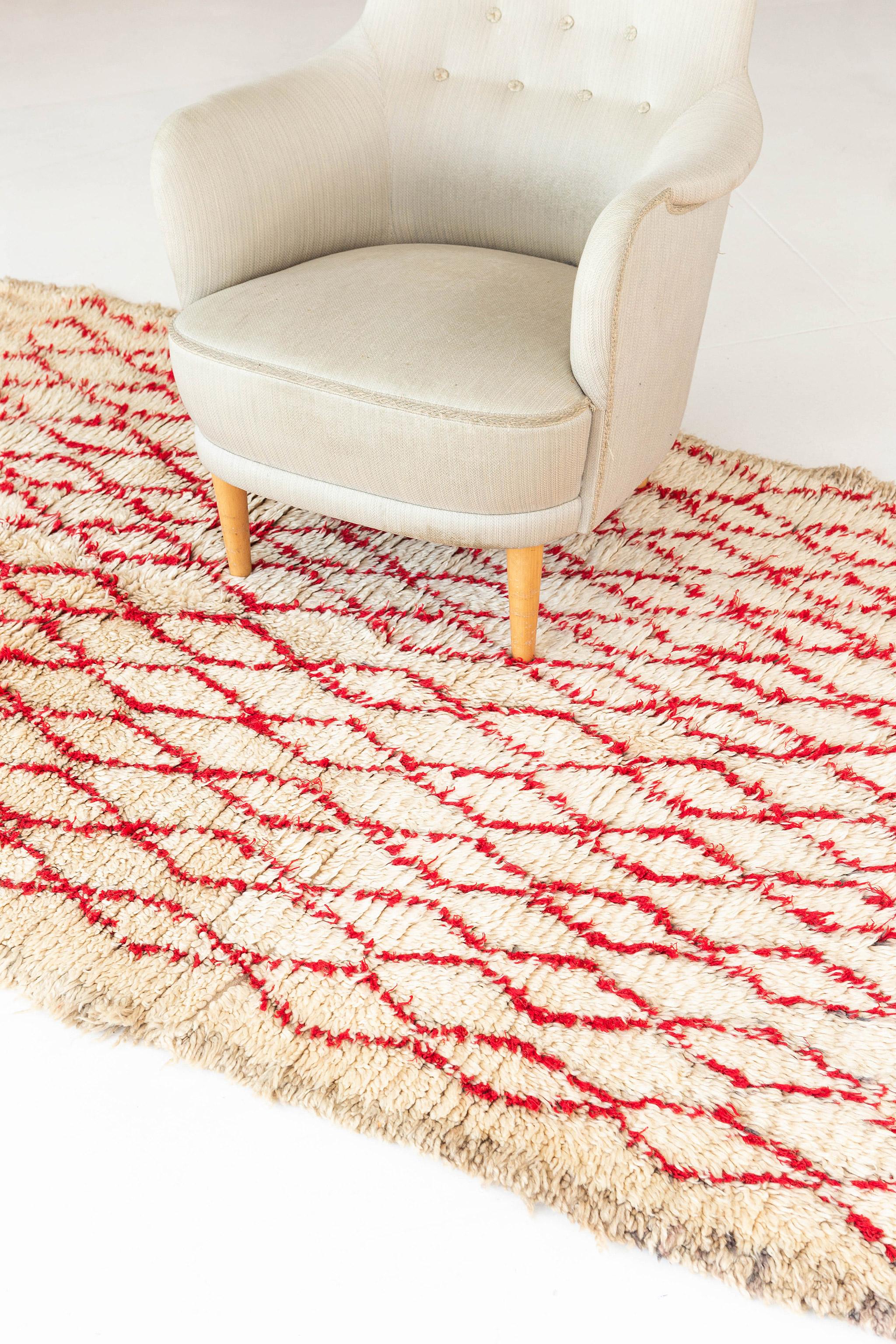 A remarkable vintage Azilal tribal rug from our Atlas Collection exhibits the symbolism including recognizable lozenges. An interesting story narrated by the skillful weavers that are open to interpretation. Knotted in shades of red and surrounded